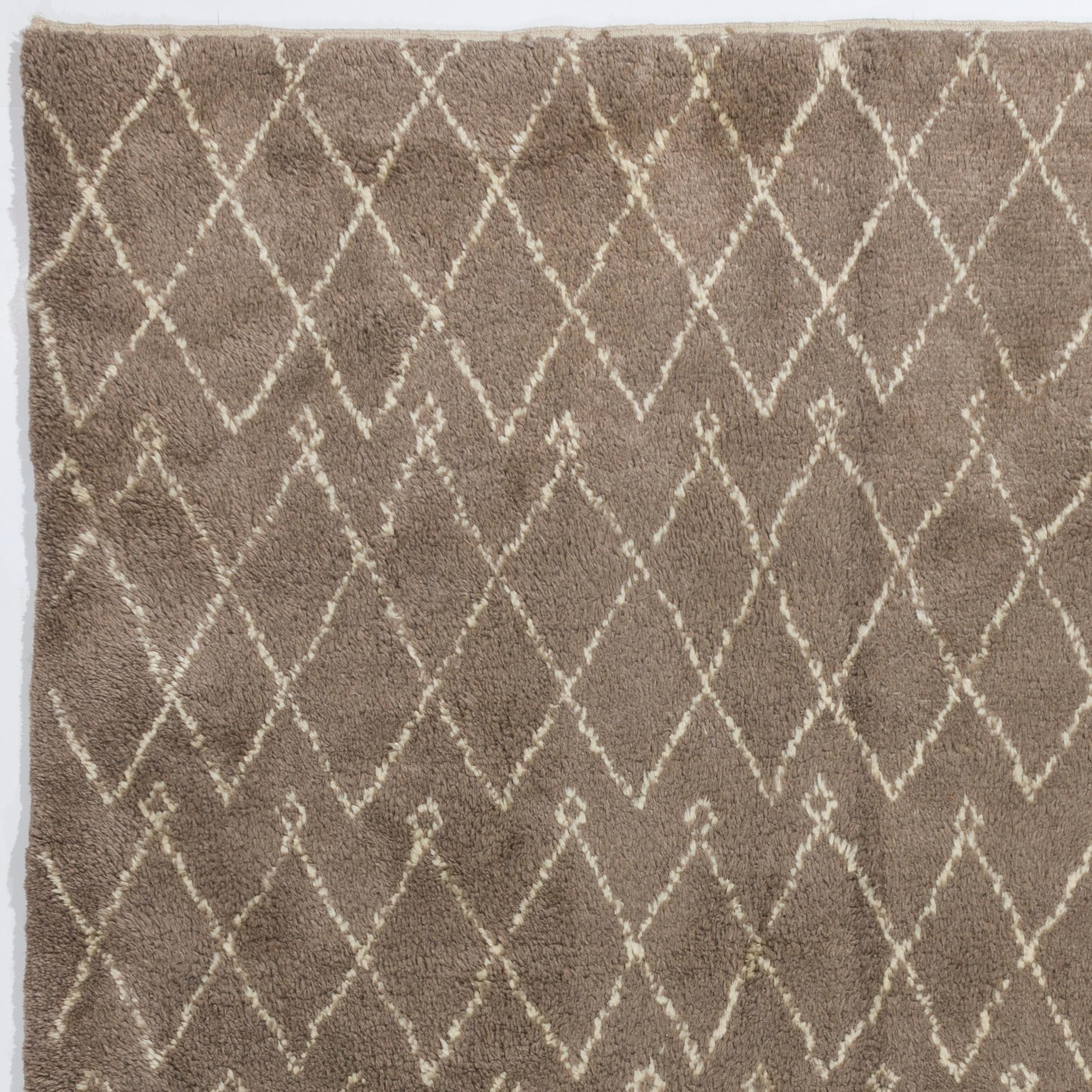 Un tapis marocain d'une beauté tranquille, composé de losanges ivoires imbriqués sur un fond latte. Tissé à la main avec de la laine d'agneau douce et naturelle non teintée, il présente un poil épais et luxuriant. Ses couleurs douces et discrètes