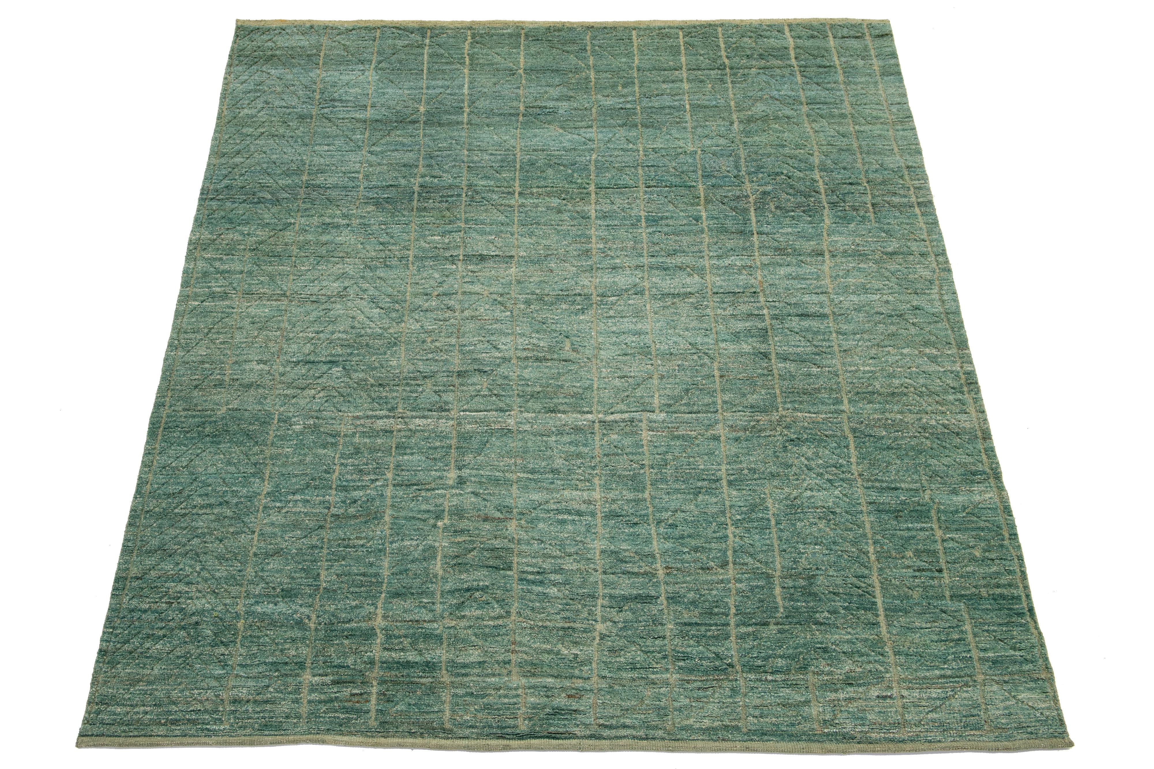 Esta excepcional alfombra de lana orgánica marroquí anudada a mano llama la atención por su vibrante fondo verde, bellamente complementado con detalles en beige y llamativos diseños geométricos. Es realmente un centro de mesa impresionante que eleva