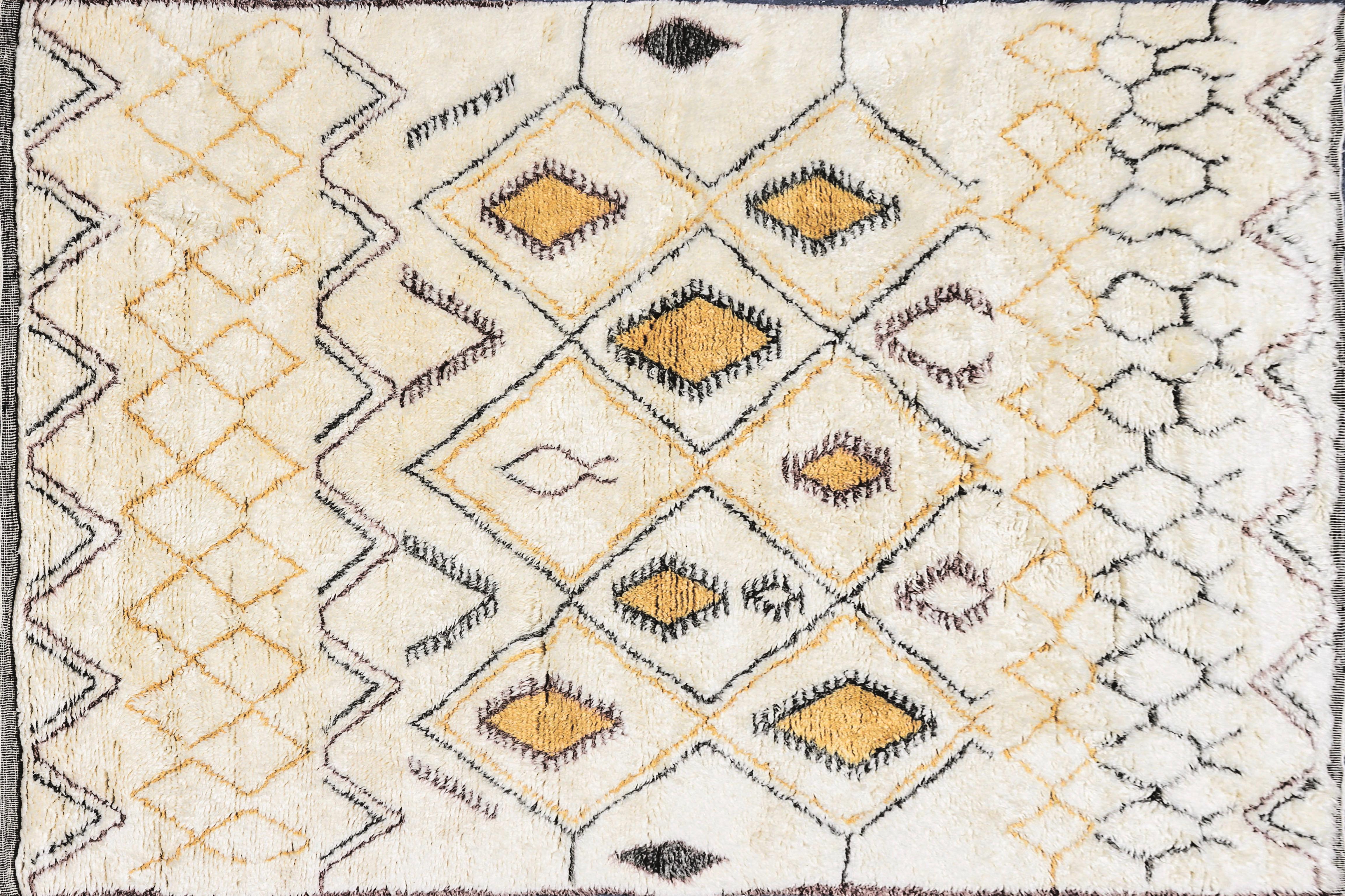 This contemporary Moroccan ivory and multi-color rug features a modern tribal geometric pattern of diamonds in golden-yellow, black and a bit of burgundy on an ivory ground. This highly durable rug with a plush 2 to 3 inch pile is hand-knotted from