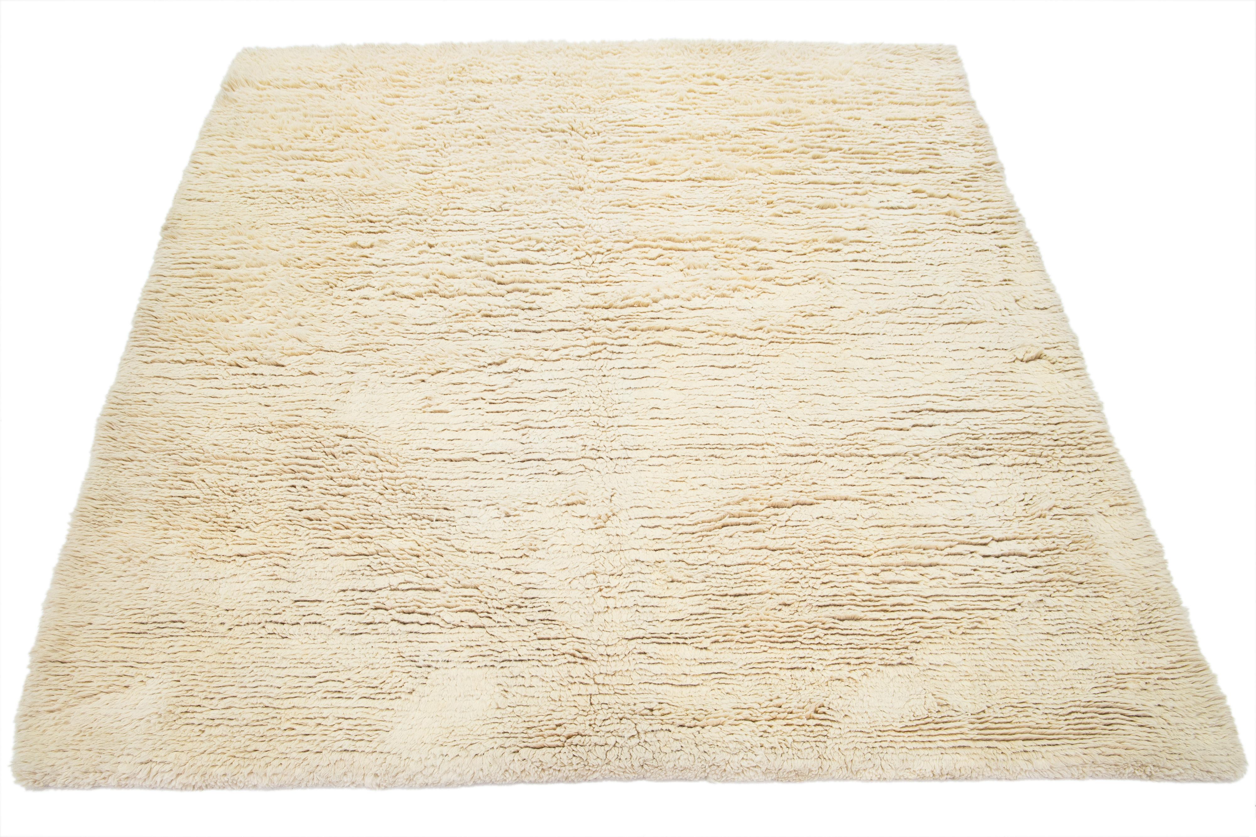 Ce tapis en laine nouée à la main présente un étonnant style Shag marocain contemporain. Il a un design solide en peluche avec un champ beige. Fabriqué avec la plus grande précision, ce tapis shag est un chef-d'œuvre qui ajoute une touche douillette