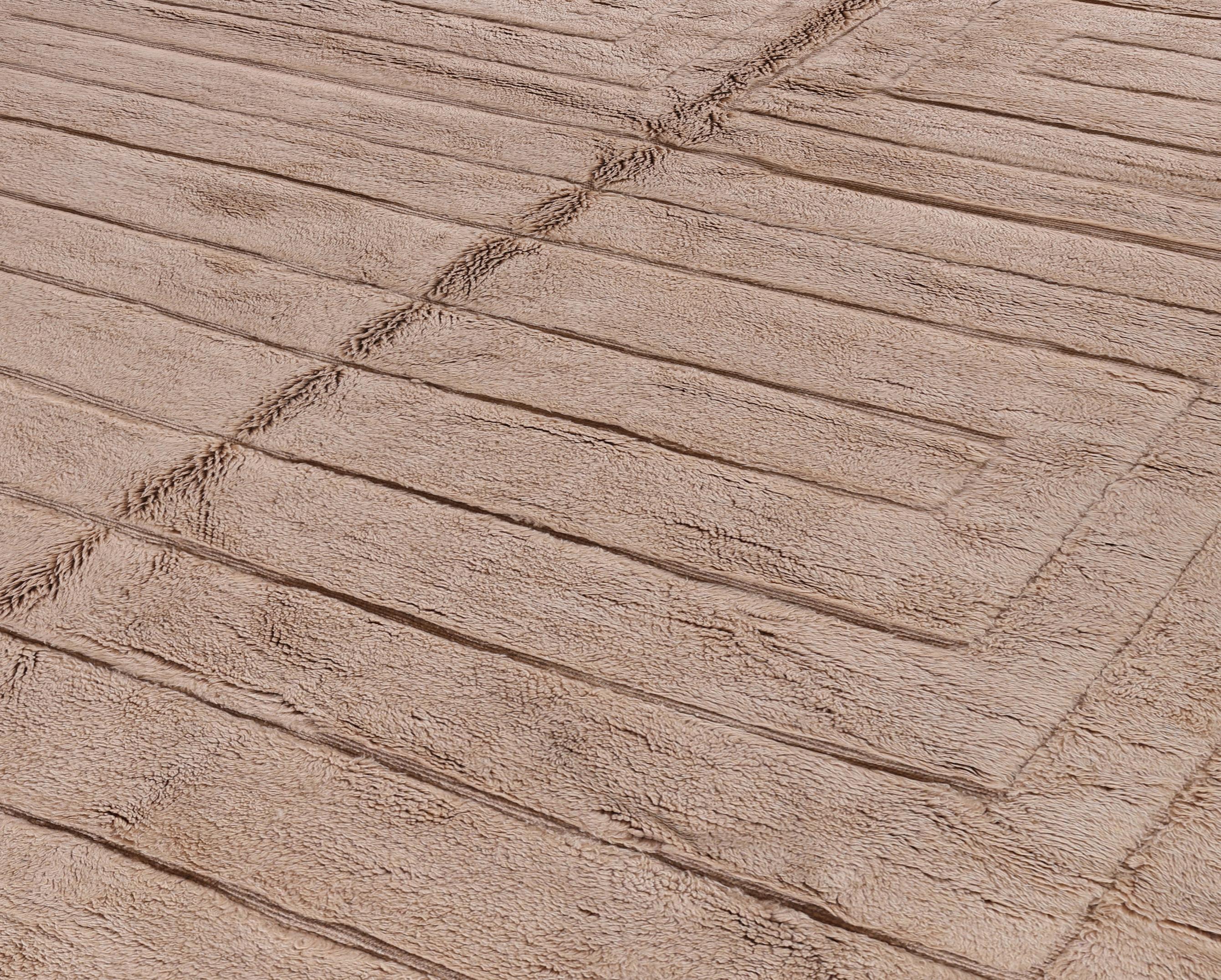 Verschönern Sie Ihren Raum mit diesem modernen marokkanischen Teppich aus handgeknüpfter beiger Wolle. Die monochrome Farbpalette wird durch ein skulpturales, lineares Reliefmuster bereichert, das durch subtile Textur und geometrischen Fluss eine