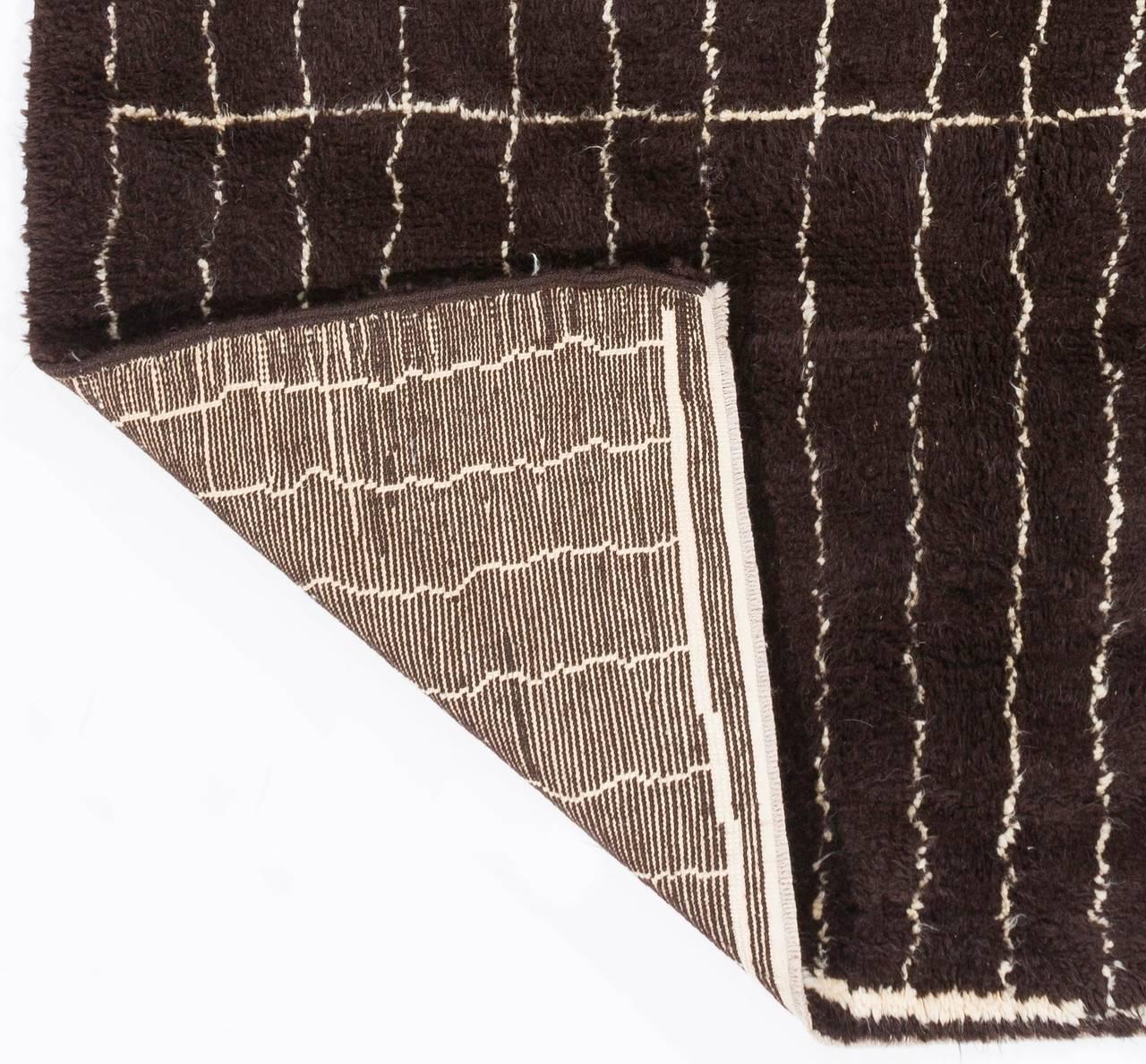 A Moroccan Berber design contemporary hand-knotted rug made of organic sheeps' wool in its original, un-dyed shades of very dark brown and cream, featuring a design of slightly crooked lines running across the length of the field with small lozenges