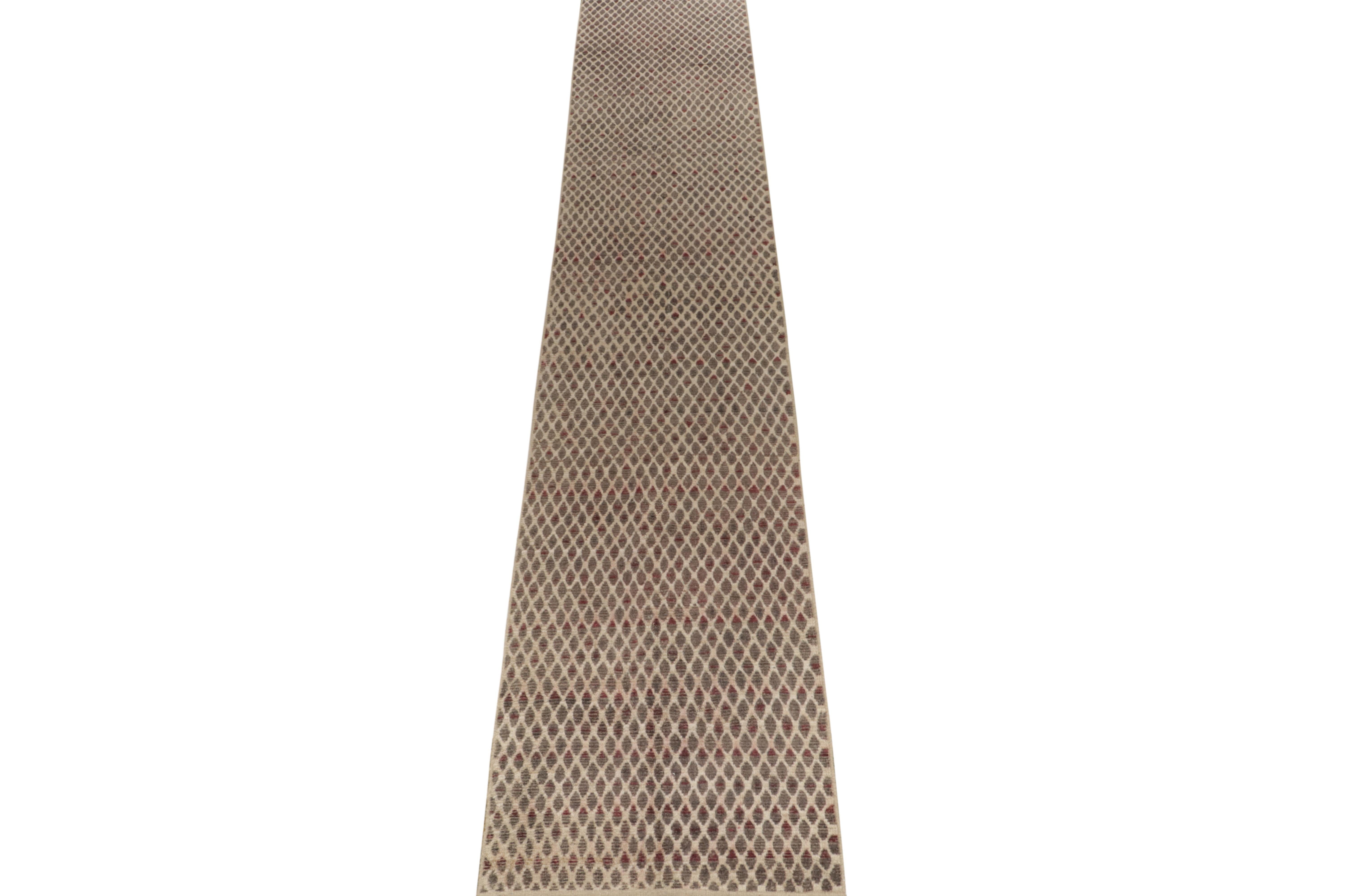 Joining our modern selections, a 3 x 19 hand-knotted wool runner embracing Moroccan aesthetics. Bearing a textural excellence, the mildly ribbed piece features a mesh like geometric pattern in beige-brown, light gray with red punctuations for a pop