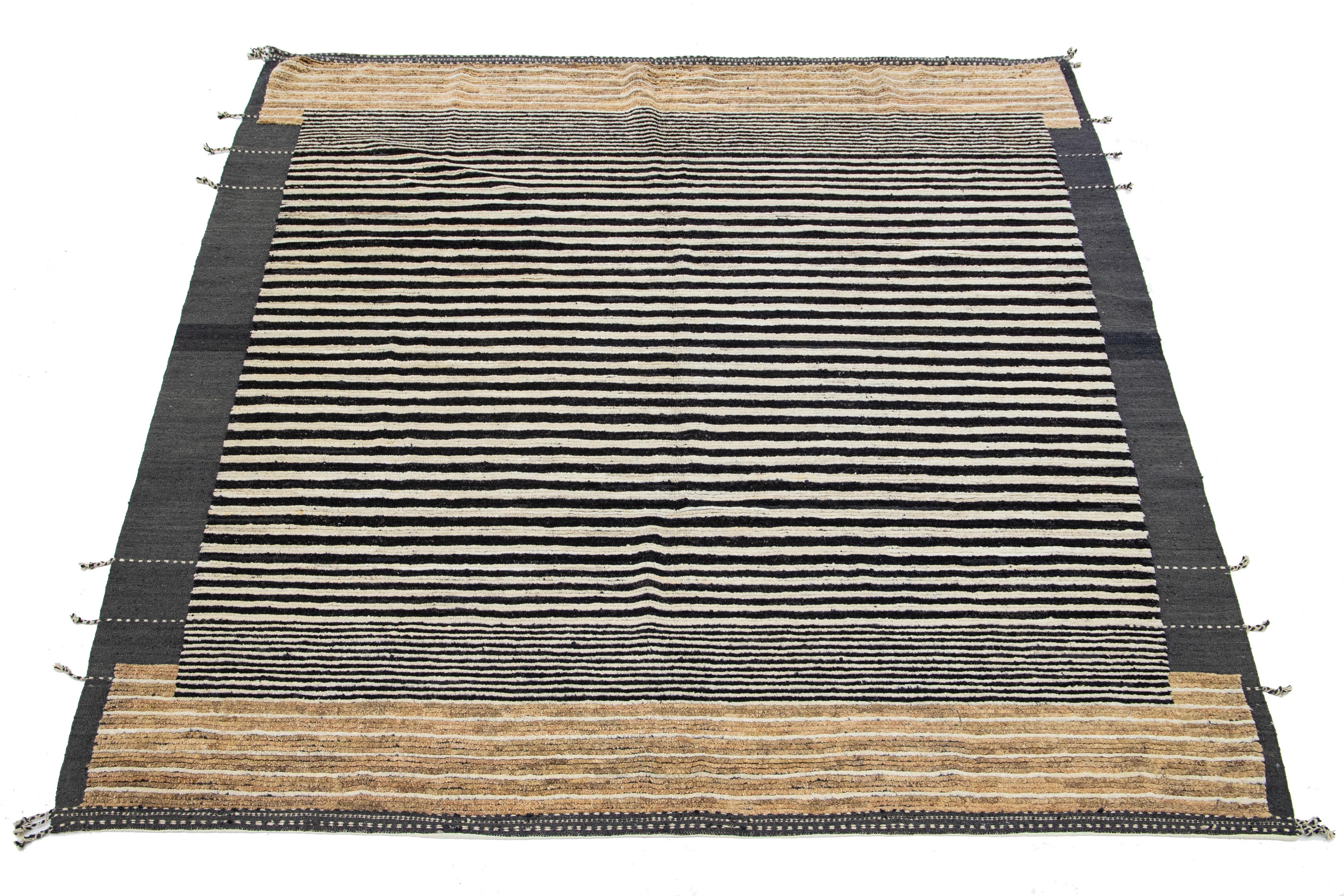 This room-size wool rug, expertly hand-knotted, showcases a Moroccan design. It exudes a contemporary appeal infused with a hint of retro styling, using an elegant mix of gray, black, and brown colors against an entrancing beige background.

This