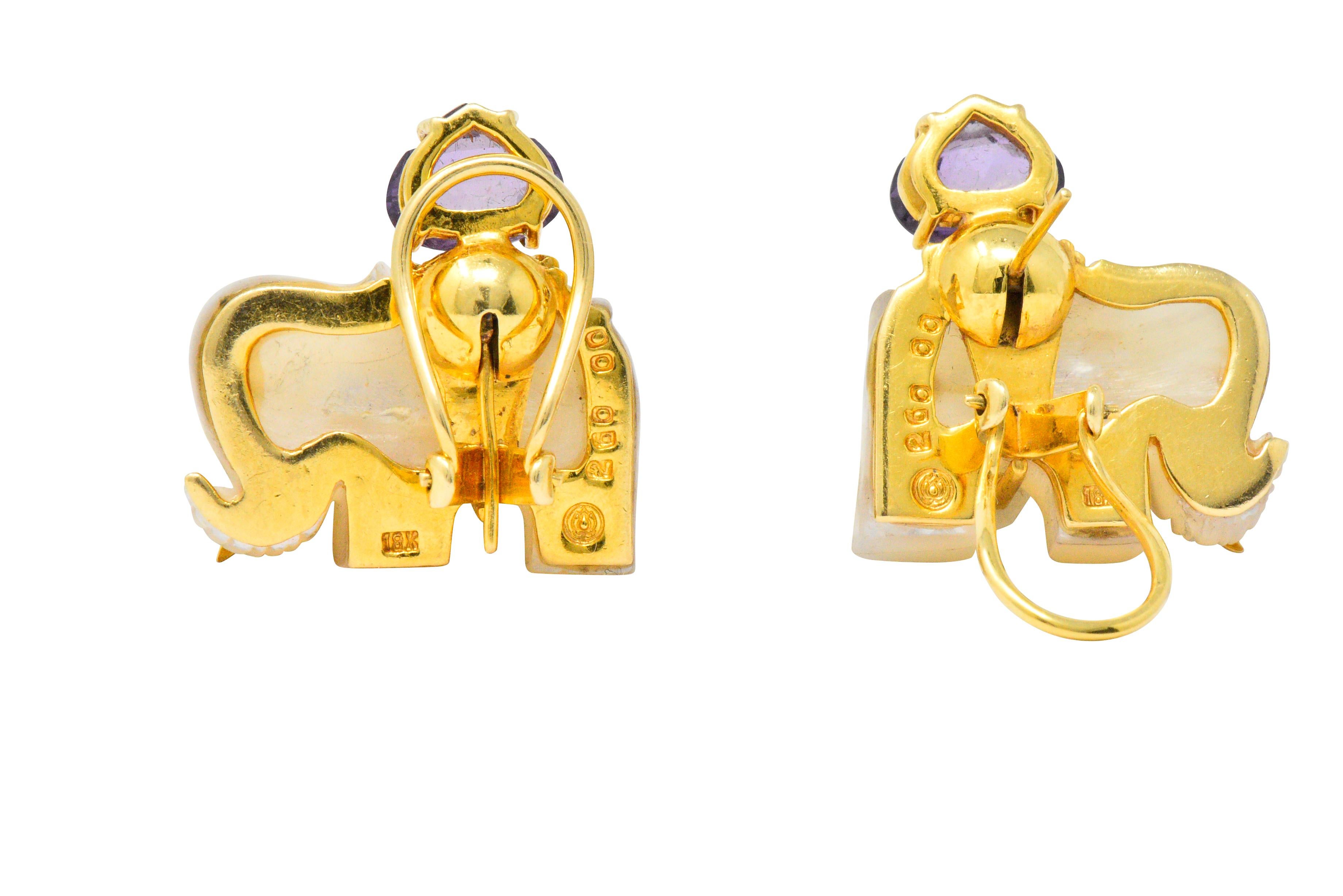 Each with mother-of-pearl carved elephant features a gold saddle, tusks and eyes

A near heart shaped, rose cut amethyst accent atop each saddle

Round brilliant cut diamond eyes, weighing approximately 0.01 carats total

Fold down posts and hinged