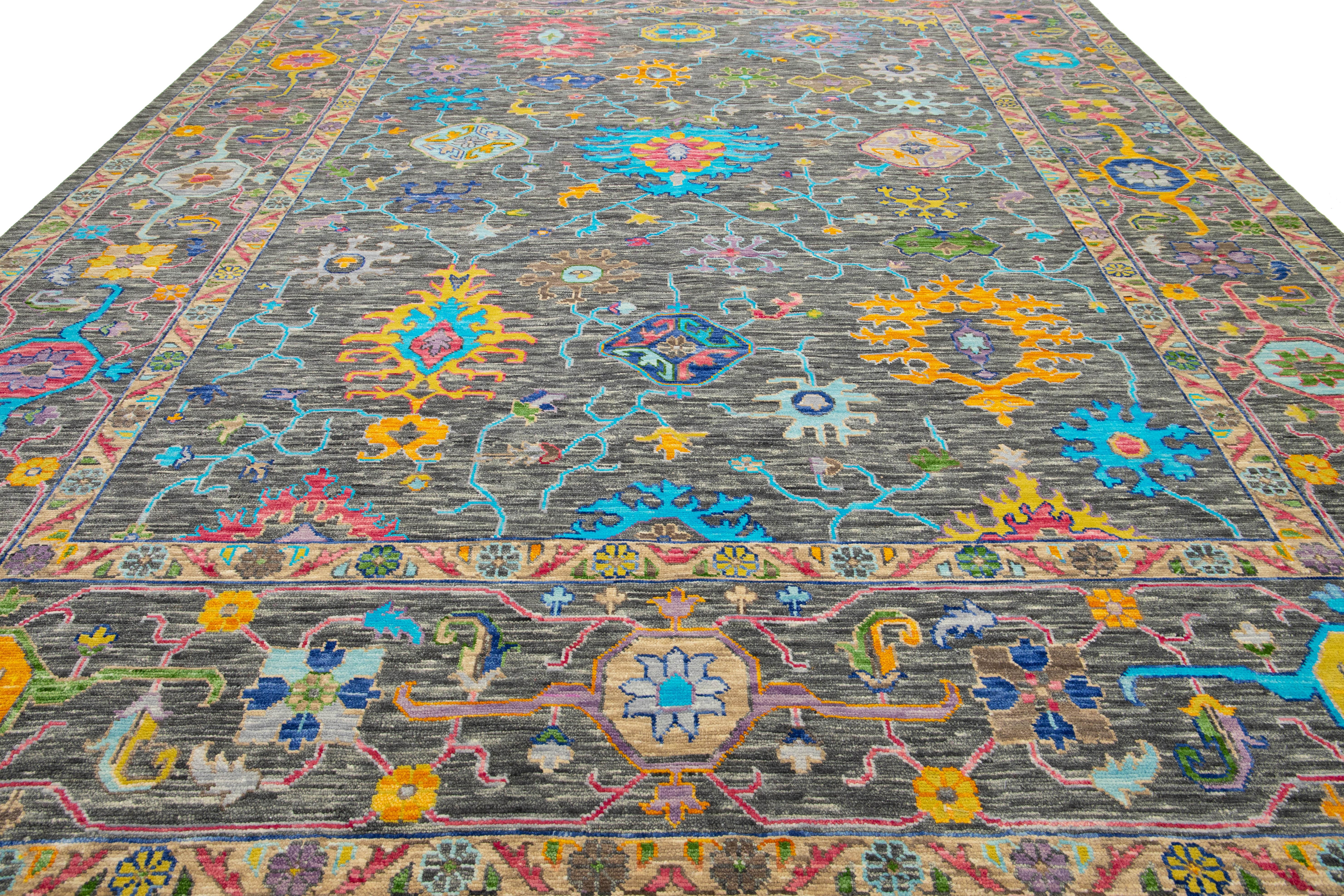 This modern Oushak-style wool rug effortlessly combines contemporary flair with the timeless elegance of traditional Oushak artistry. Featuring a striking gray background, the rug is adorned with vibrant floral patterns in a dynamic array of colors