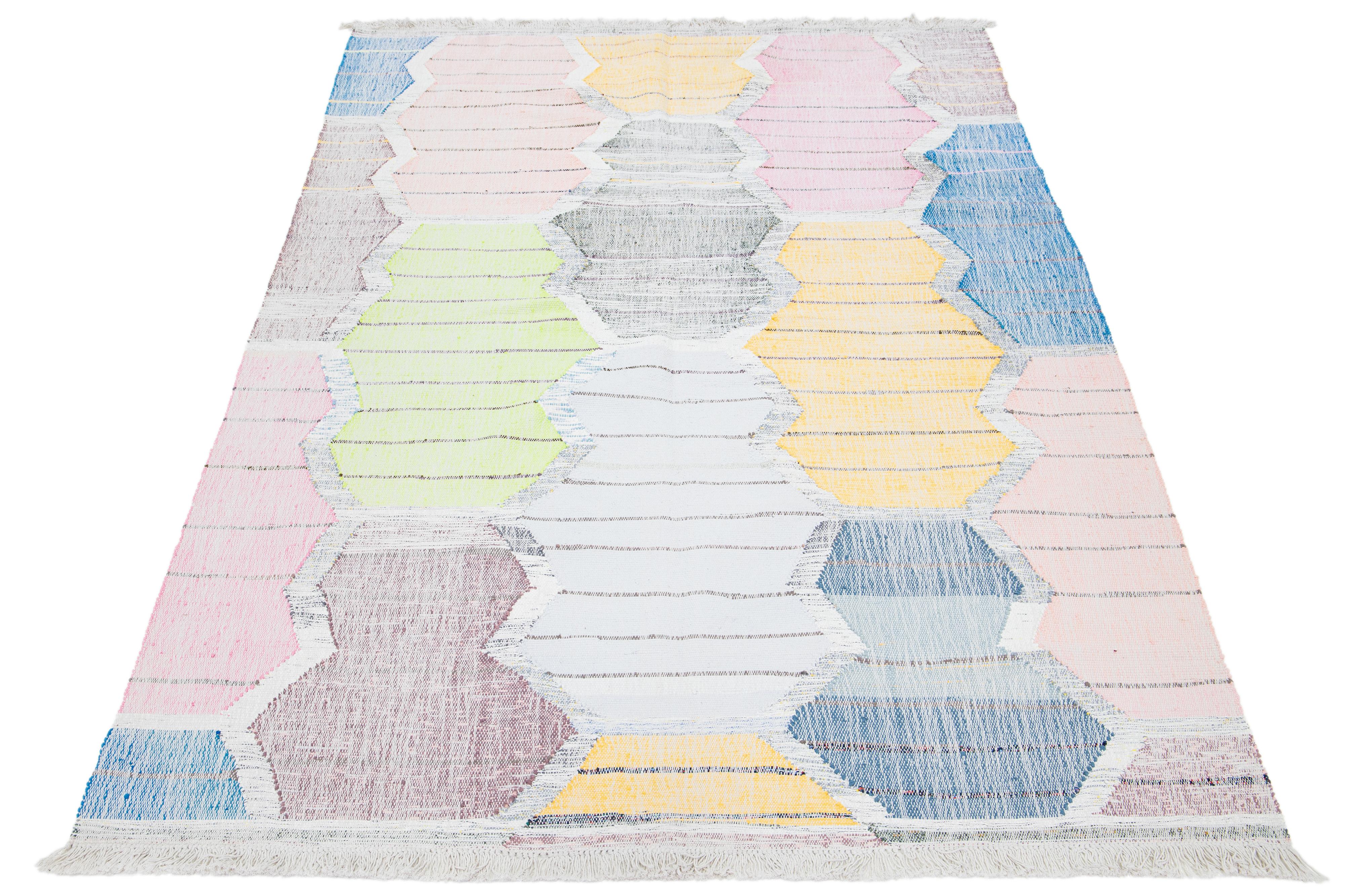 Dieser Teppich ist aus Wolle in einem modernen Kilim-Flachgewebedesign gefertigt und weist einen mehrfarbigen Untergrund mit einem geometrischen Muster auf.

Dieser Teppich misst 6'6
