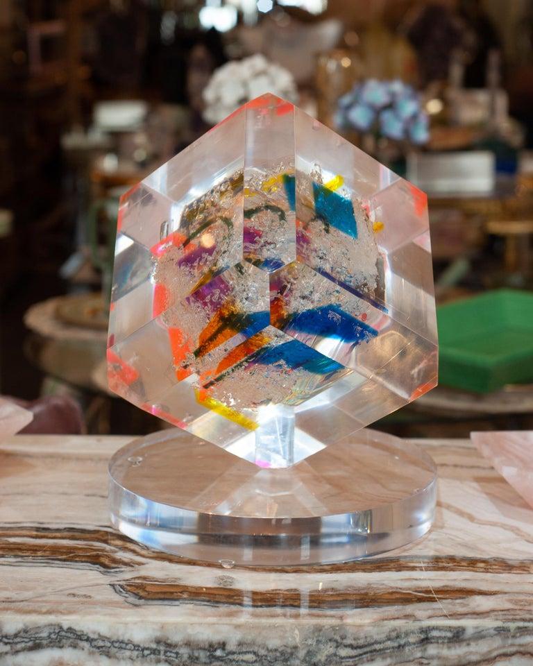A large cube sculpture by a Cuban artist, cast in crystal-clear acrylic and alive with splashes of pink, blue, orange, yellow, and green. Brilliantly vibrant and ever-shifting, it catches and refracts the light to reveal new perspectives from every