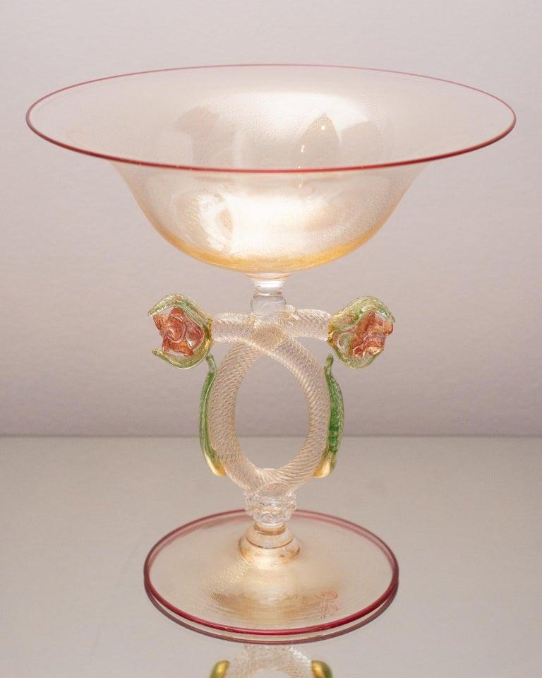 Un gran cuenco contemporáneo de Murano soplado a mano con ricos colores, adornado con dos flores de color rubí creadas por un maestro soplador de vidrio. El cuenco con pie está hecho de vidrio al que se han incorporado fragmentos de pan de oro para