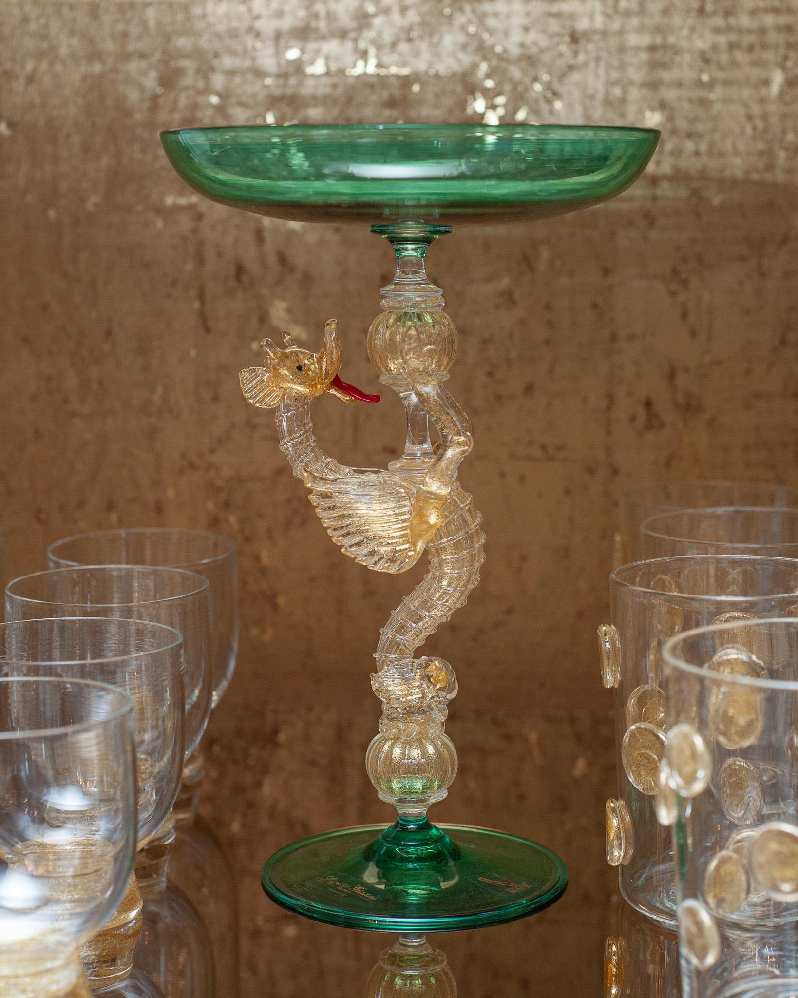A stunning contemporary hand blown Murano compote with rich blue green coloured bowl and foot, supported by a gold leaf infused dragon. Created by a master glass blower, this footed bowl incorporates fragments of gold leaf to give the piece a warm