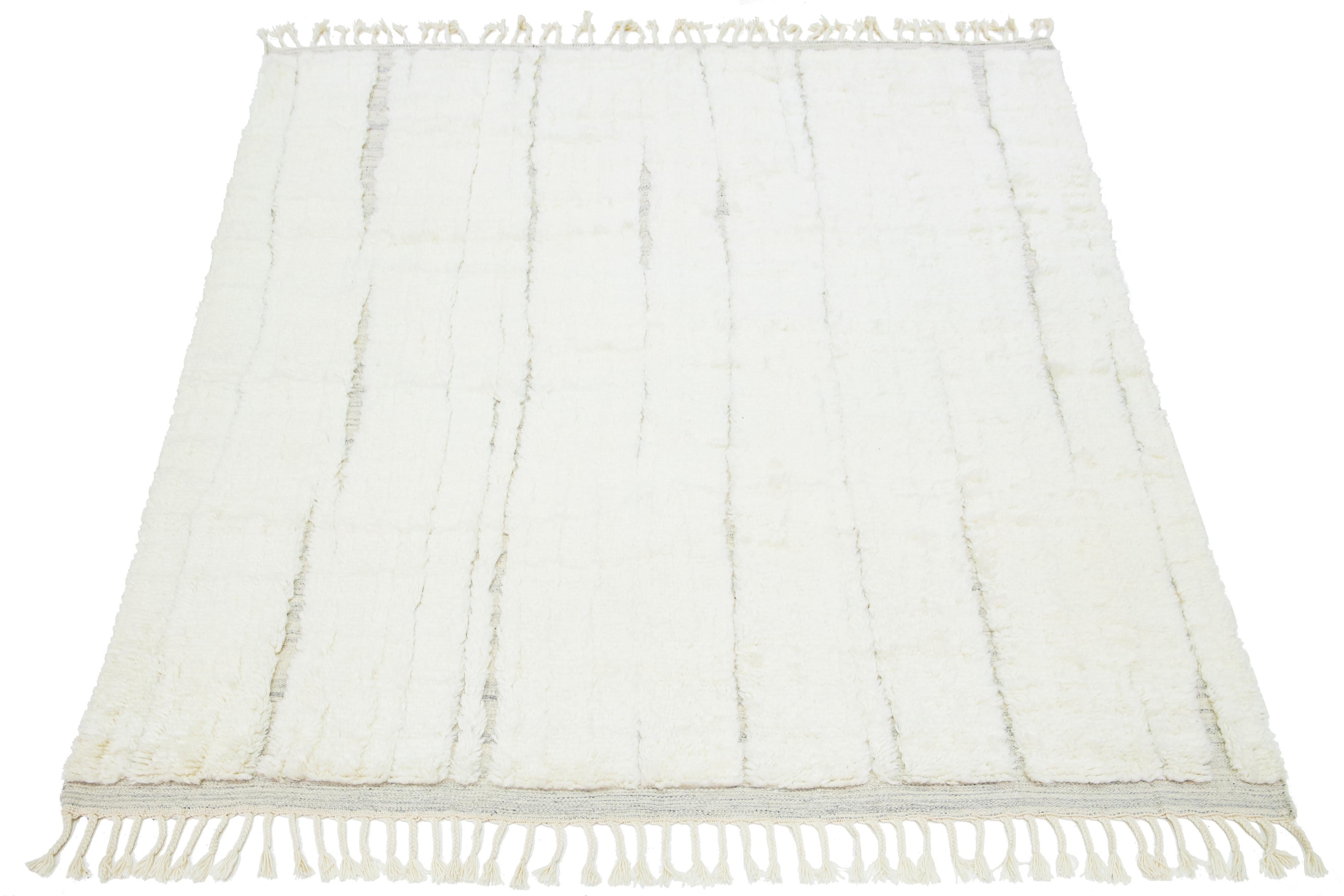 This beautiful, modern Moroccan-style, hand-knotted wool rug features a natural ivory field. It is a part of our Apadana Safi Collection and highlights a stunning, soft, linear design with fringes on the ends.

This rug measures 8' x 10'.