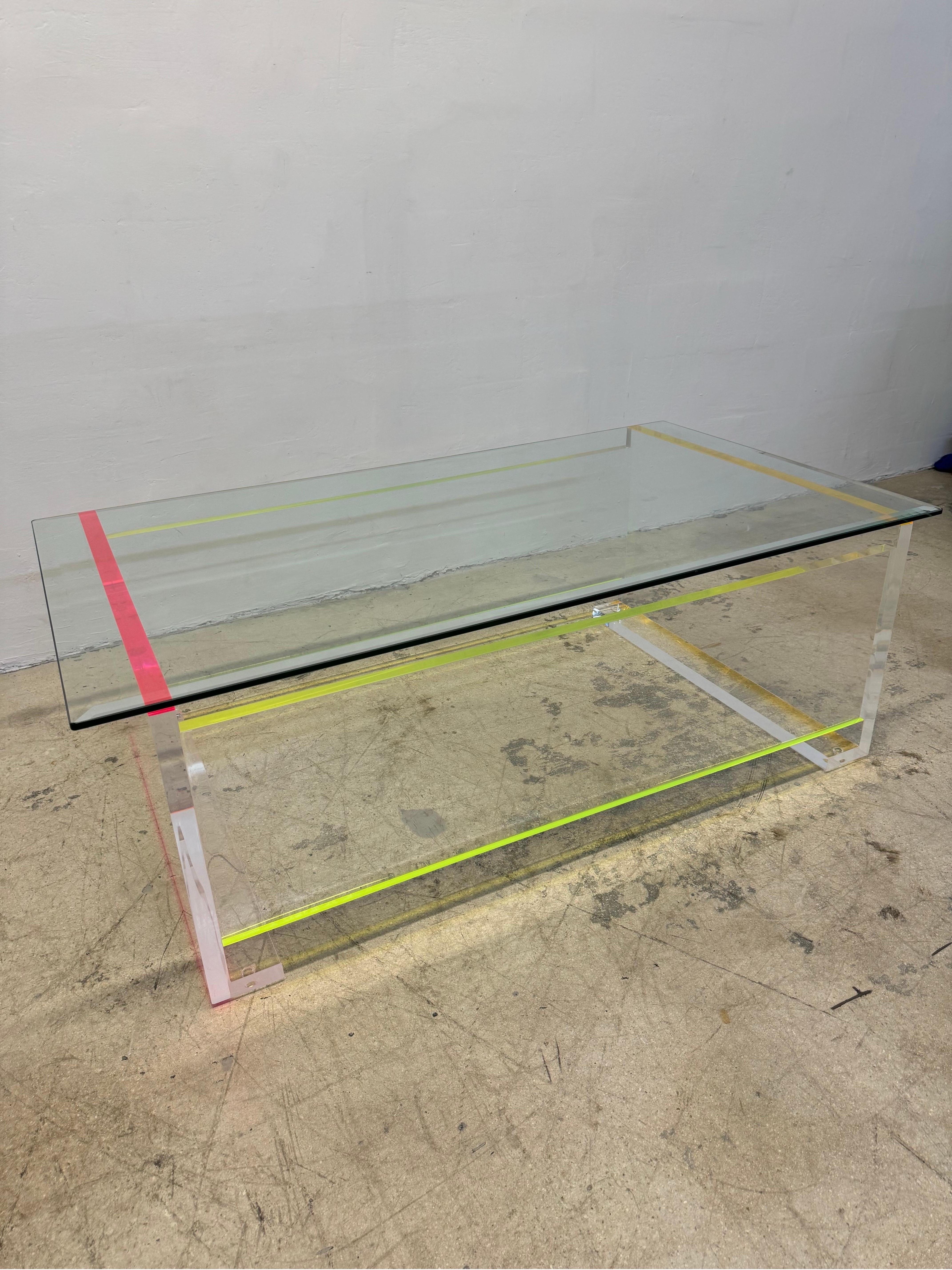 Modern neon color edge thick lucite / acrylic coffee or cocktail table with bevel edge glass top circa 1990s.  The lucite is 1-1/2” thick with neon edge strips in pink, yellow and orange.  The glass 1/2” with 1” bevel.

Base Only Dimensions (without