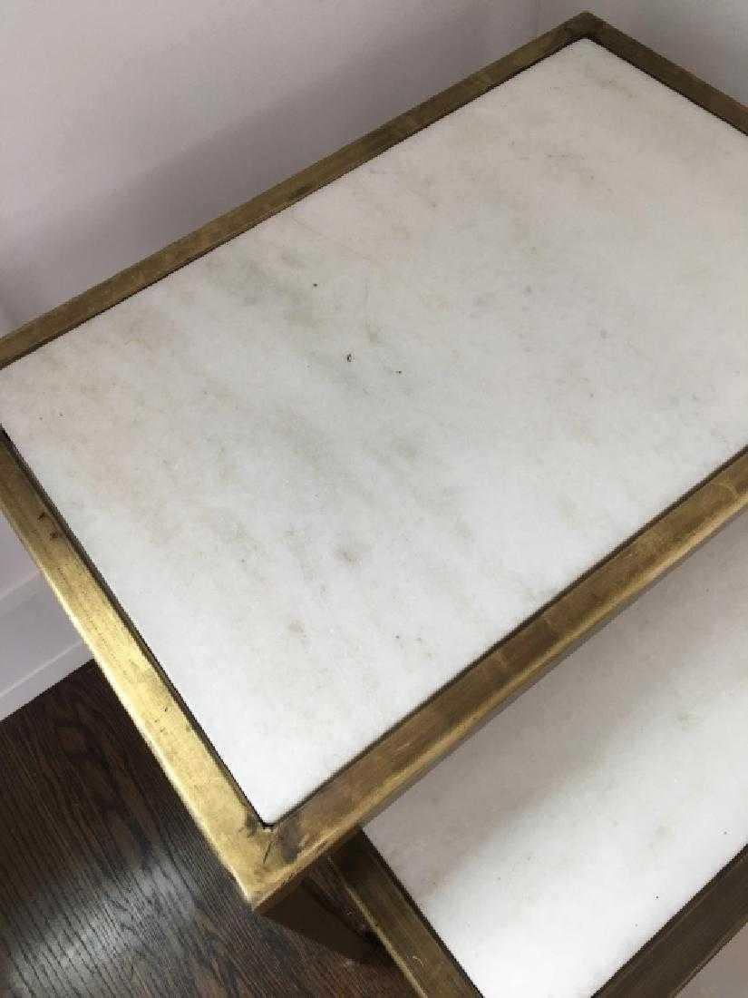 Three contemporary marble top nesting tables. Three graduated size stacking tables in a contemporary or modern style with white marble table tops and brass frames and legs. Can be used as end of side tables. Largest measures: 16 inches x 24 inches x