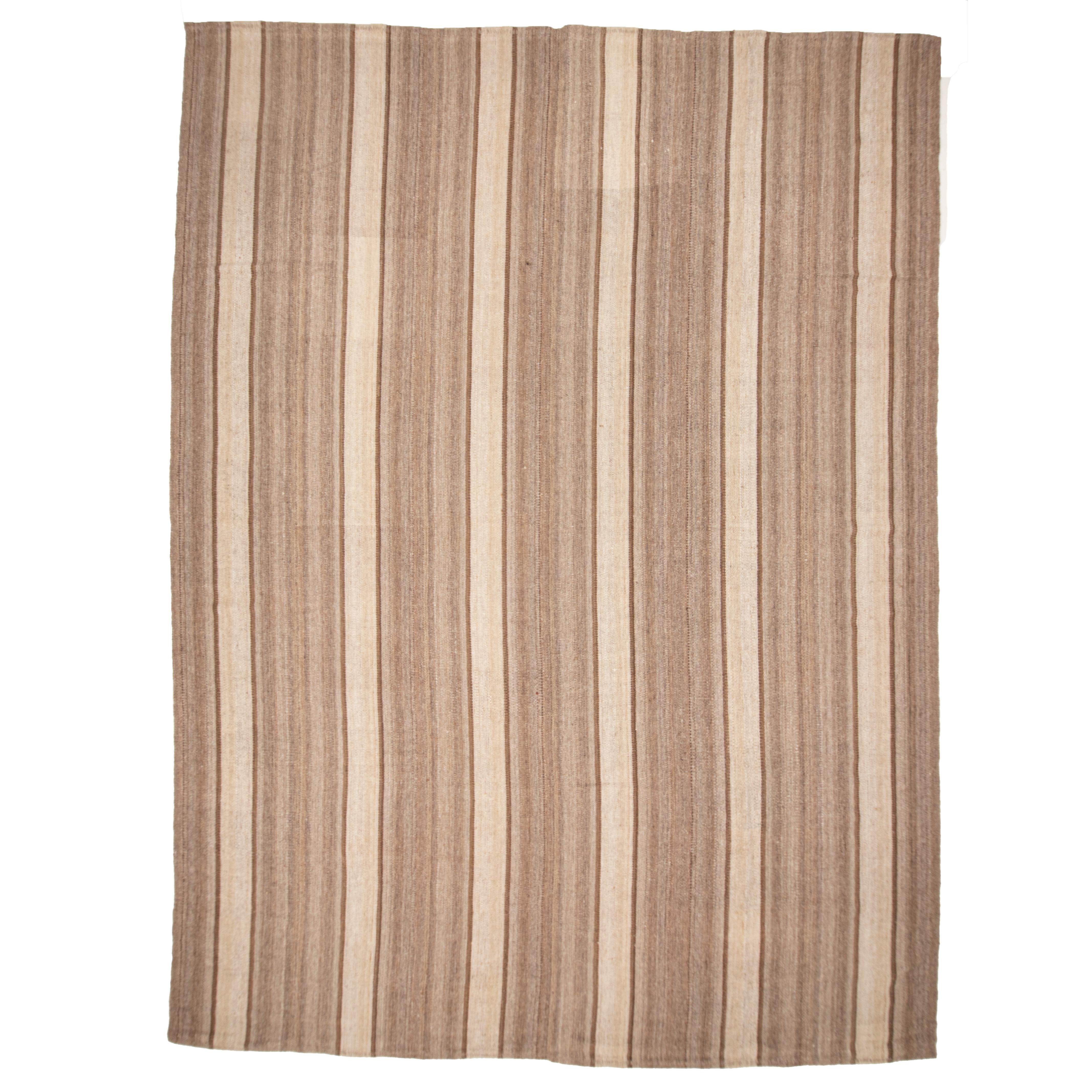 This kilim is woven with undyed wool yarns in narrow stripes and then hand stitched . It has a soft handle.

