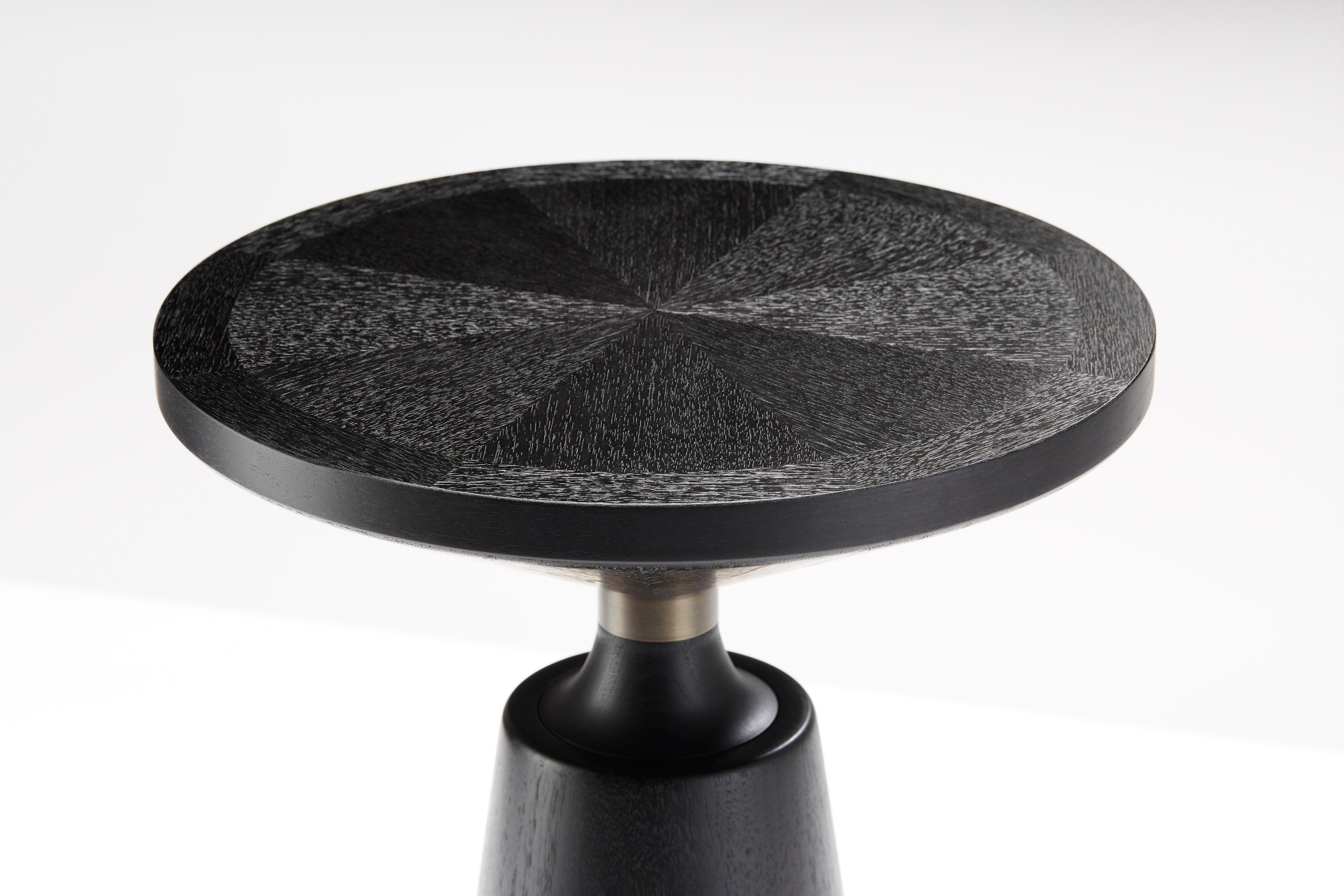 Esta edición Tuxedo de una de nuestras piezas más célebres, la Mesa auxiliar Nicole, está expertamente torneada a partir de gruesas secciones de madera maciza curada. Presenta una tapa chapada de corte radial especial con marcas cruzadas. Una