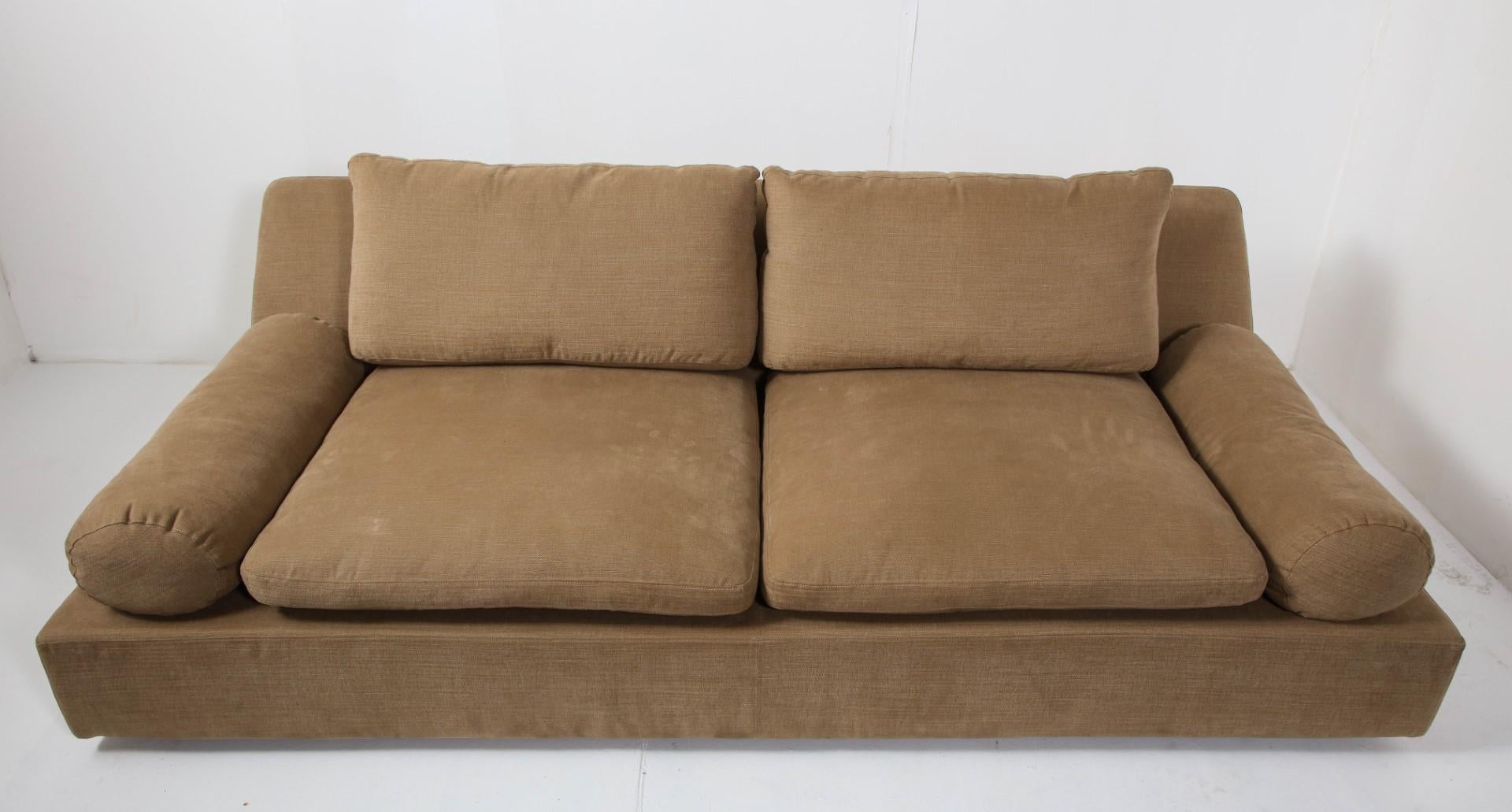 Contemporary low-slung Nube Italia two-seat Tender sofa designed by Carlo Colombo, tan cotton upholstery with bolster arms. Foam & feather seat cushions; back cushion and bolsters in feather. Like-new condition. 

Measures: Arm height 19