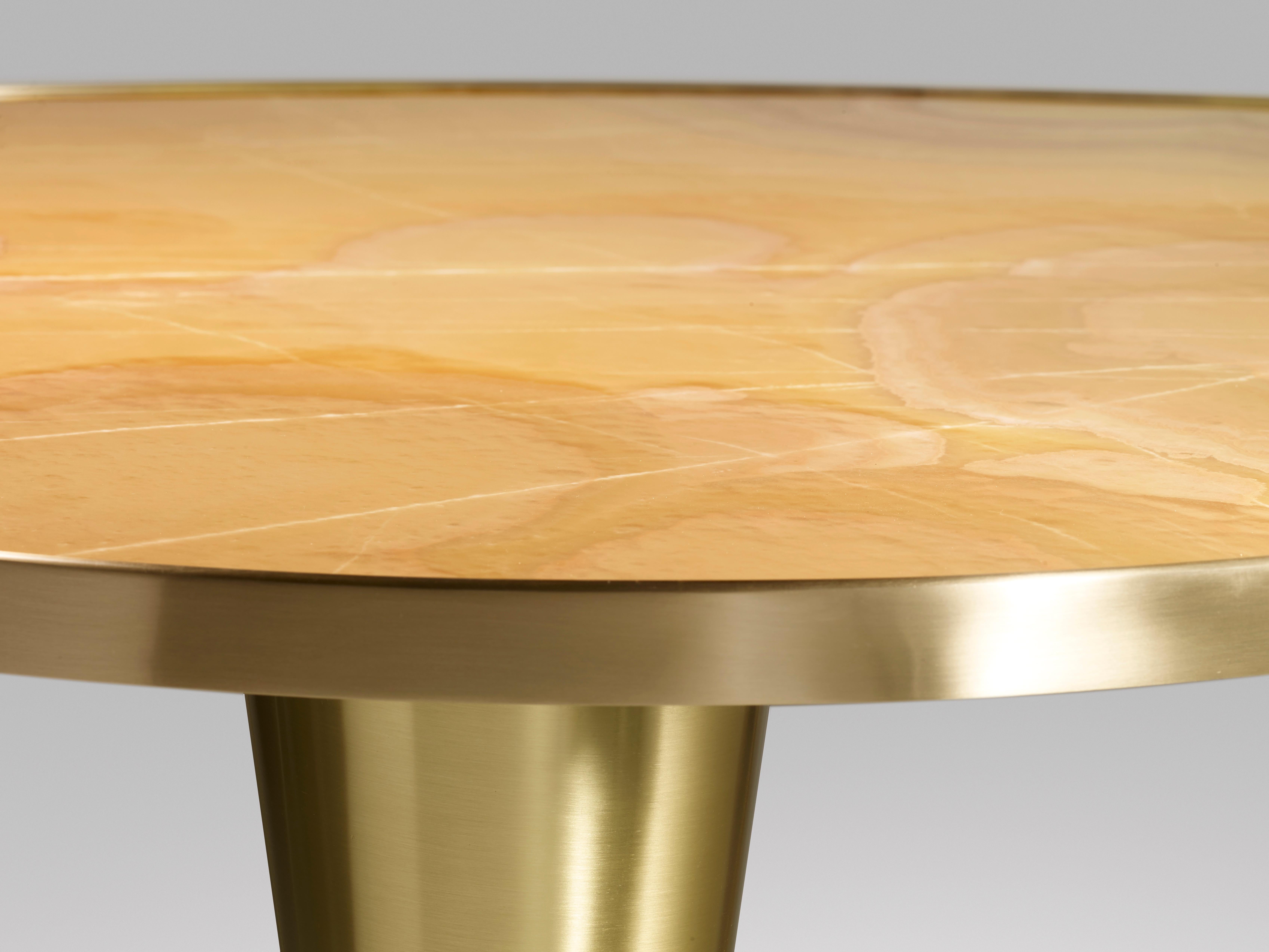 Contemporary dining table with top in polished honey onyx and double inverted-cone legs in satin brass.  