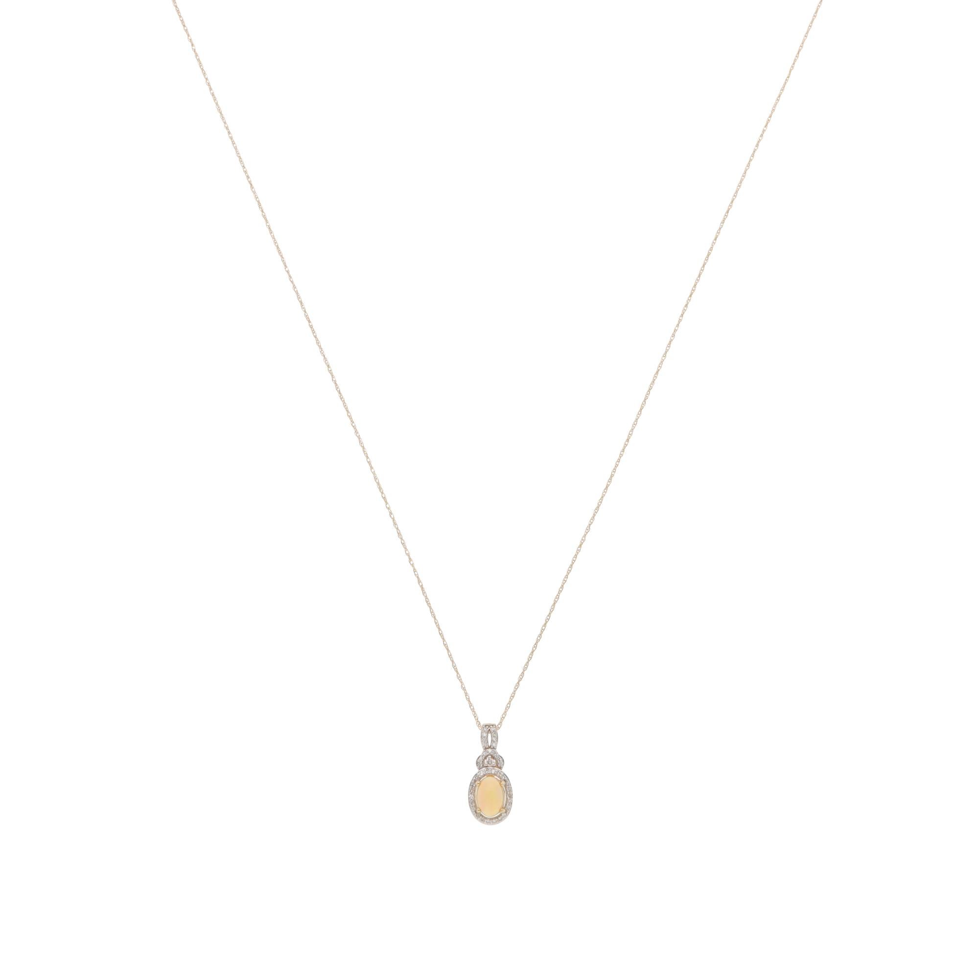 A beautiful contemporary precious opal and diamond cluster pendant necklace set in 14k yellow gold.

The pendant is predominately prong-set with an oval cabochon precious opal with play-of-colour, surrounded by 38 round brilliant-cut diamonds. The