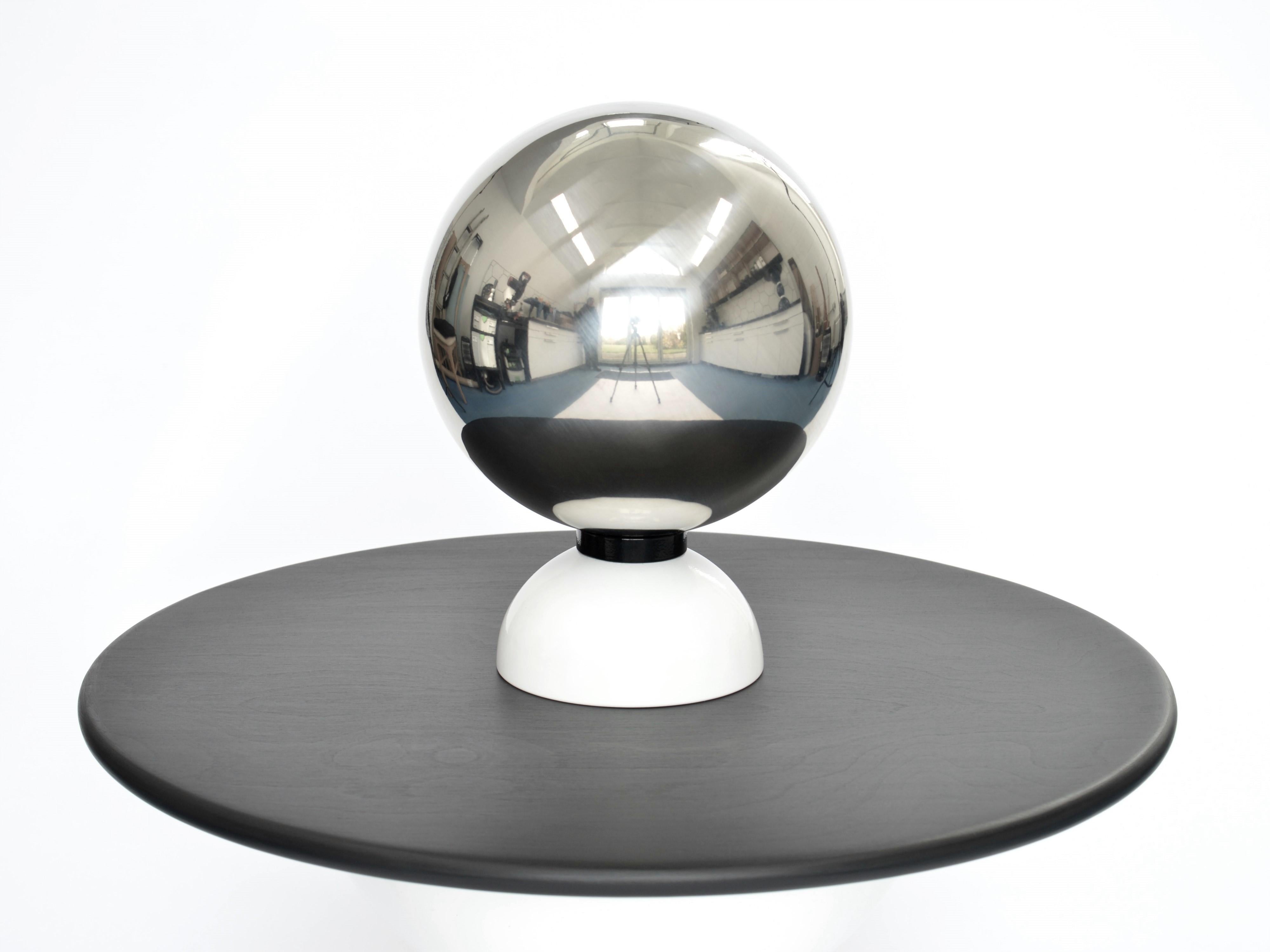 The Orb Mirror is a decorative table top mirror, featuring a polished stainless steel orb, fixed to a powder coated steel base. Like M.C. Escher's famous self portrait 'Hand with Reflecting Sphere', the viewer sees themselves within a three