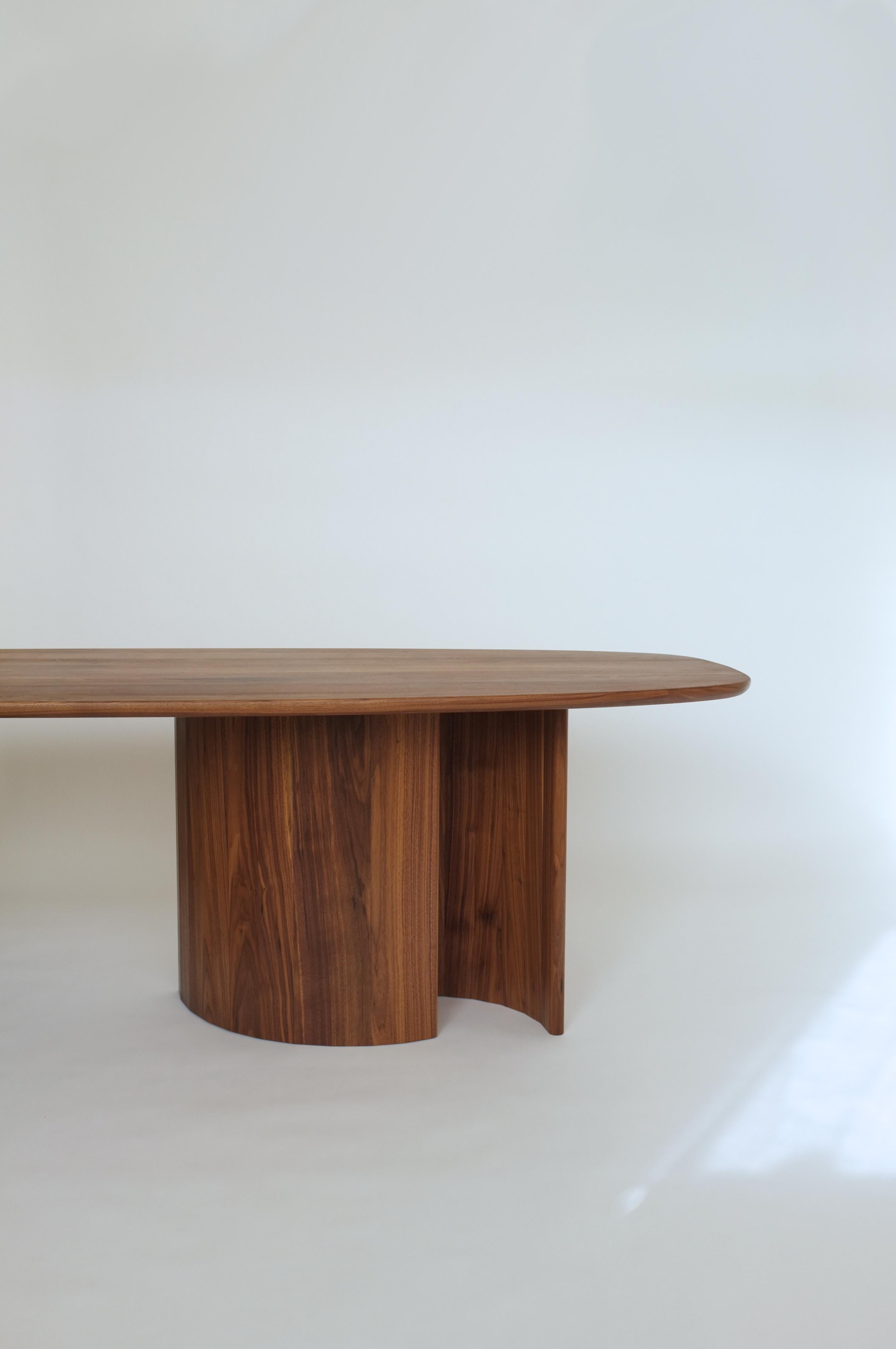 Dining table for Richard by Campagna in walnut.

This sculptural, contemporary wooden dining table features a free flowing, organic top and faceted, arc-shaped legs. The interaction of the three uniquely curved legs creates moments of shifting