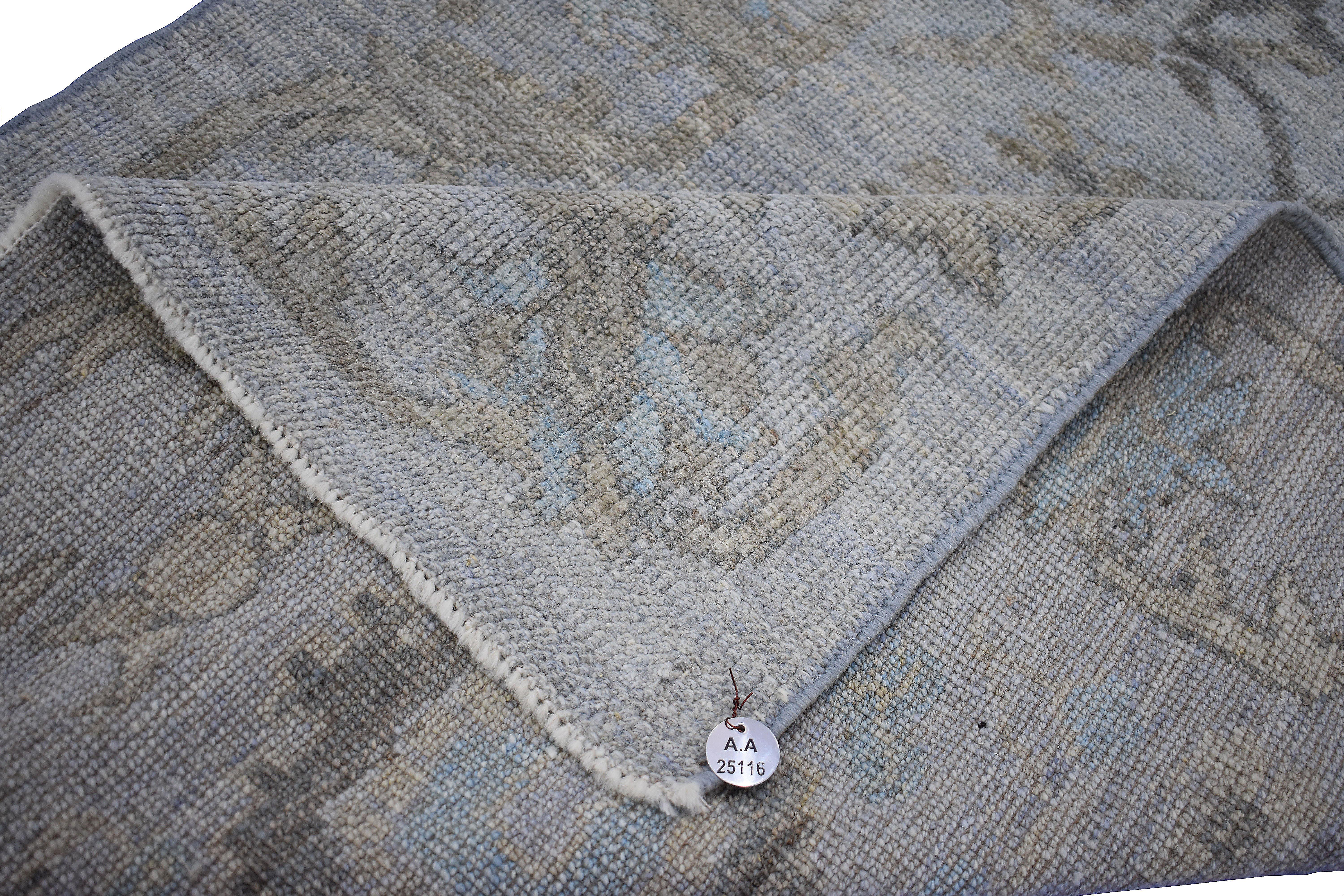 Moderner türkischer Teppich aus handgewebter Schafwolle von höchster Qualität. Es ist mit organischen Pflanzenfarben gefärbt, die für Menschen und Haustiere gleichermaßen als sicher zertifiziert sind. Es zeigt ein grau-violettes Feld mit floralen