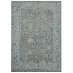 Zeitgenössischer Oushak-Teppich mit grauer Fläche und blauer Bordüre mit Blumenmotiv