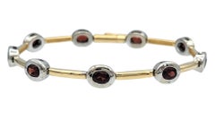 Pulsera contemporánea con granates de talla ovalada en oro de 14 quilates bicolor