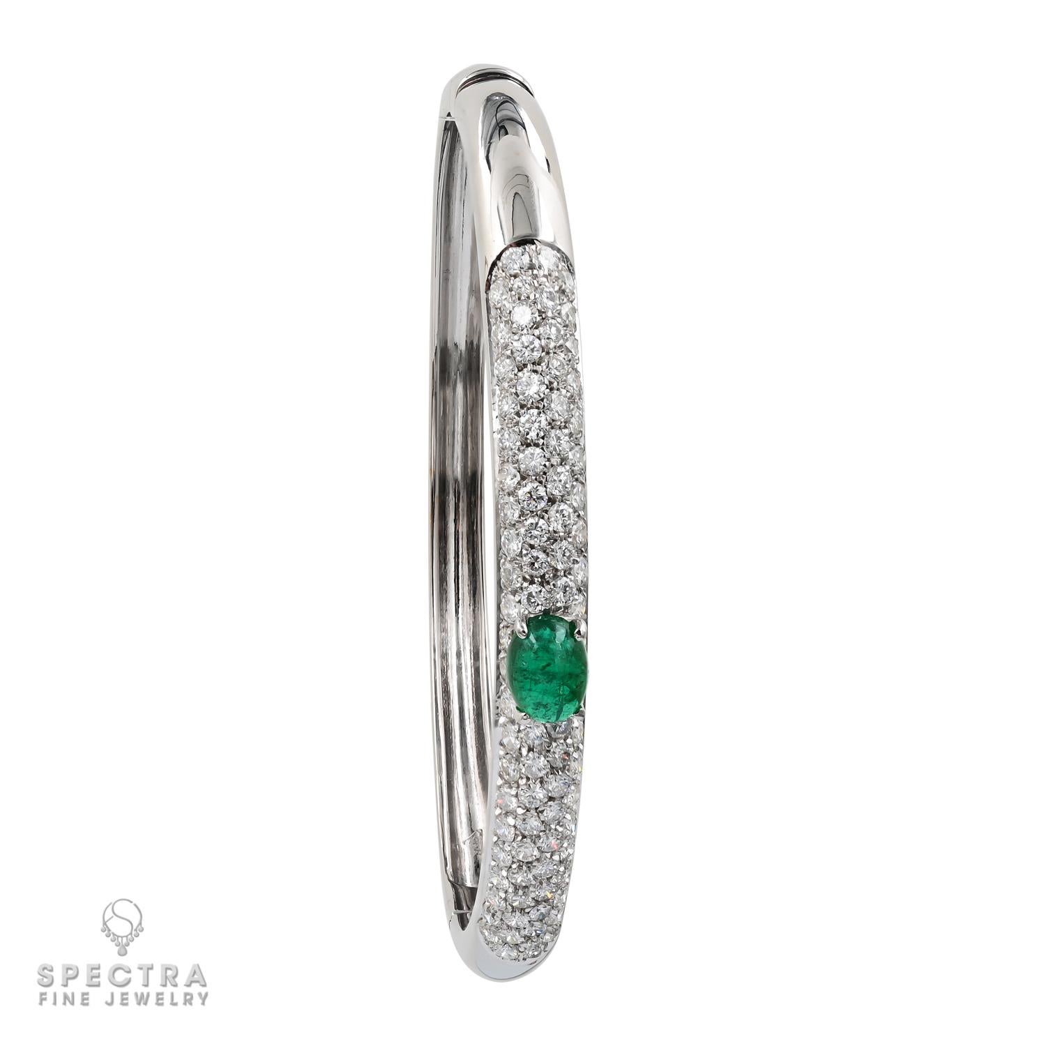 This Contemporary Oval Emerald Diamond Pavé Bombe Bangle Bracelet, made in the 21st century, is a classic hinge bangle in the bombé style. The domed shape is pleasingly rounded yet narrow. The curved surface allows the natural beauty of the diamonds