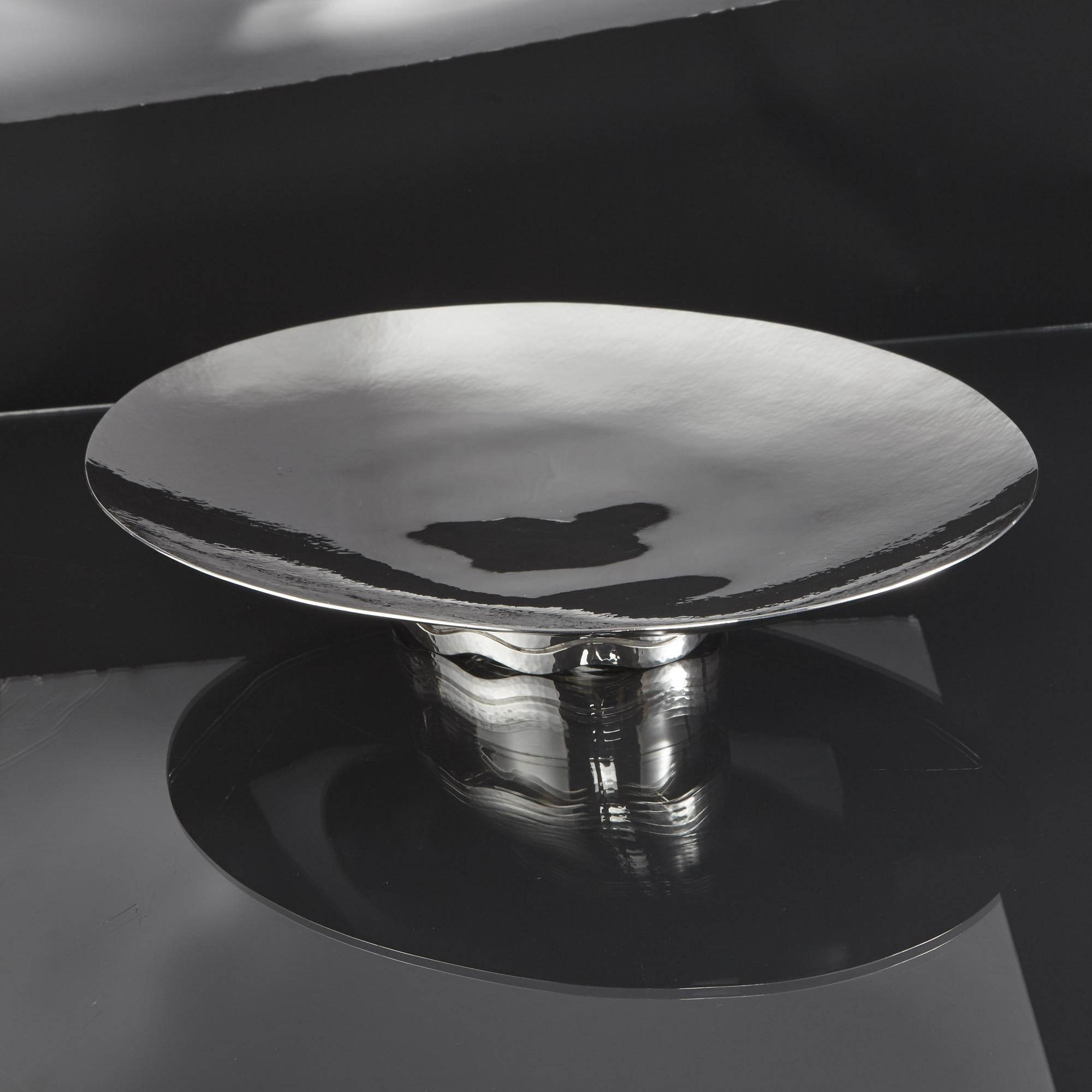 Large and elegant contemporary hammered silver table centrepiece of oval form. The silver dish or shallow bowl is hand hammered around the edge, tapering to a plain central area. The collet base is fitted with a cast, hand-hammered wavy band