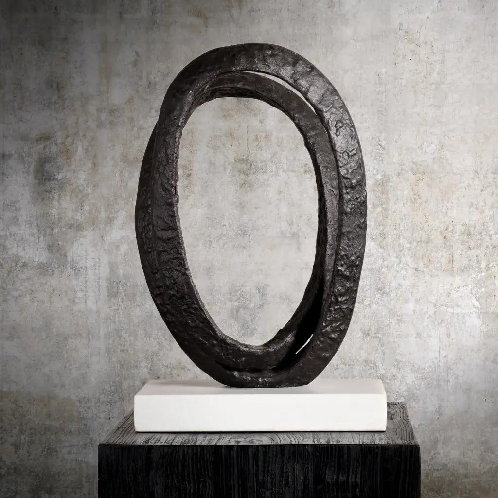 Contemporary sculpture in black/brown metal, featuring an irregular metal ring set on a light-colored base. The contemporary sculpture reflects a brutalist style.

Dimensions: H 51 × W 33 × D 20 cm
Please contact us before ordering to confirm