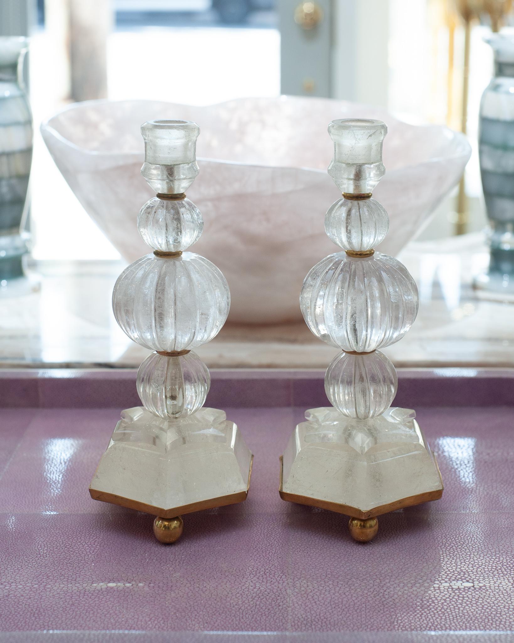 This pair of rock crystal and bronze candlesticks was sourced in Paris. Each feature scalloped rock crystal balls and carved rock crystal star motifs with brass base. Rock crystal has long been used in decoration and many ornate pieces are exhibited