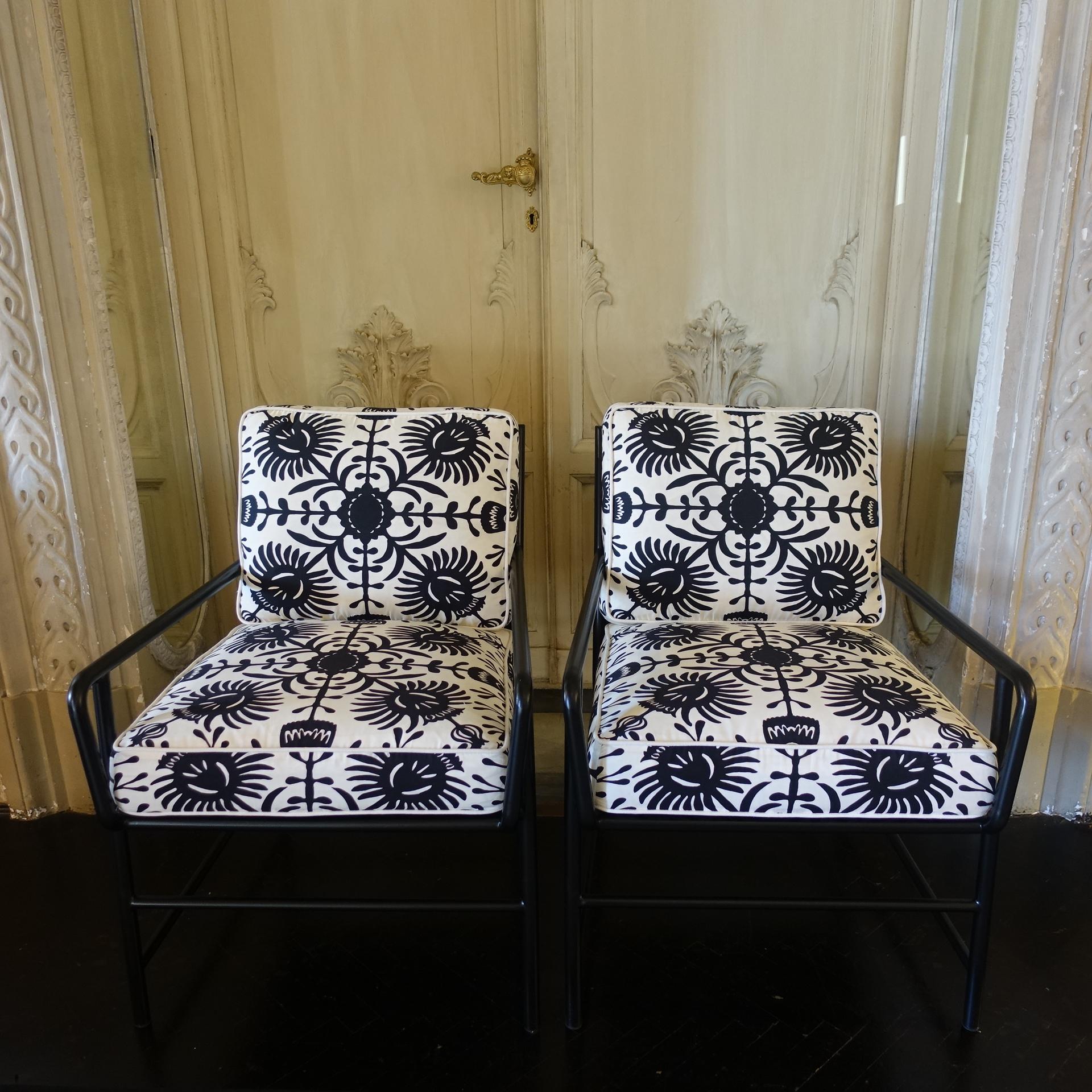 One of a kind pair of contemporary armchairs with black metal frame and perforated backrest with hexagonal motif, newly upholstered seat and back cushion in black and white floral print.