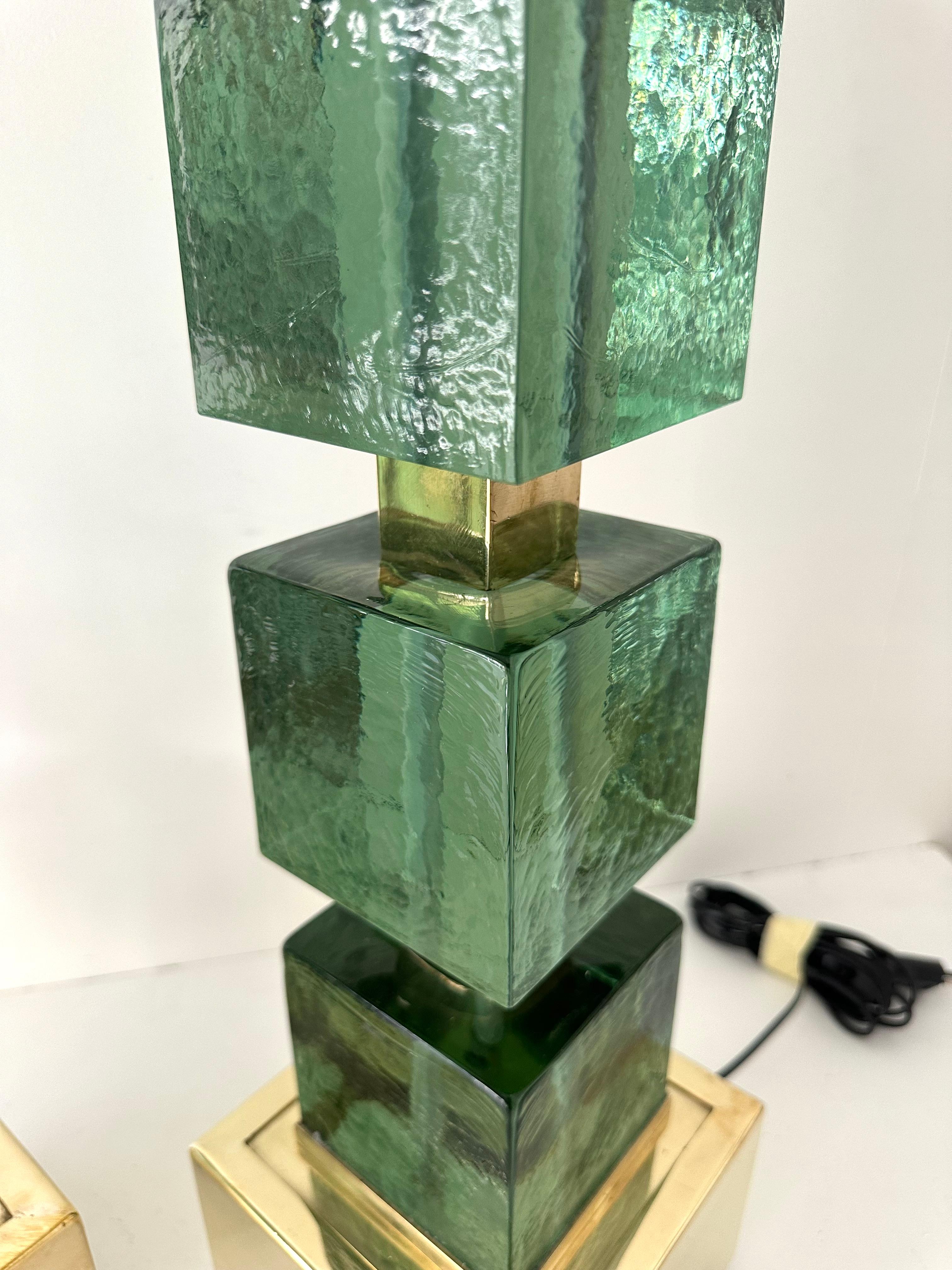 Pair of table or bedside brass lamps and green Murano glass cube. Contemporary work from a small italian artisanal workshop, minor imperfections due to artisanal handmade. in a Mid-Century Modern Space Age Hollywood Regency mood.

Demo shades are