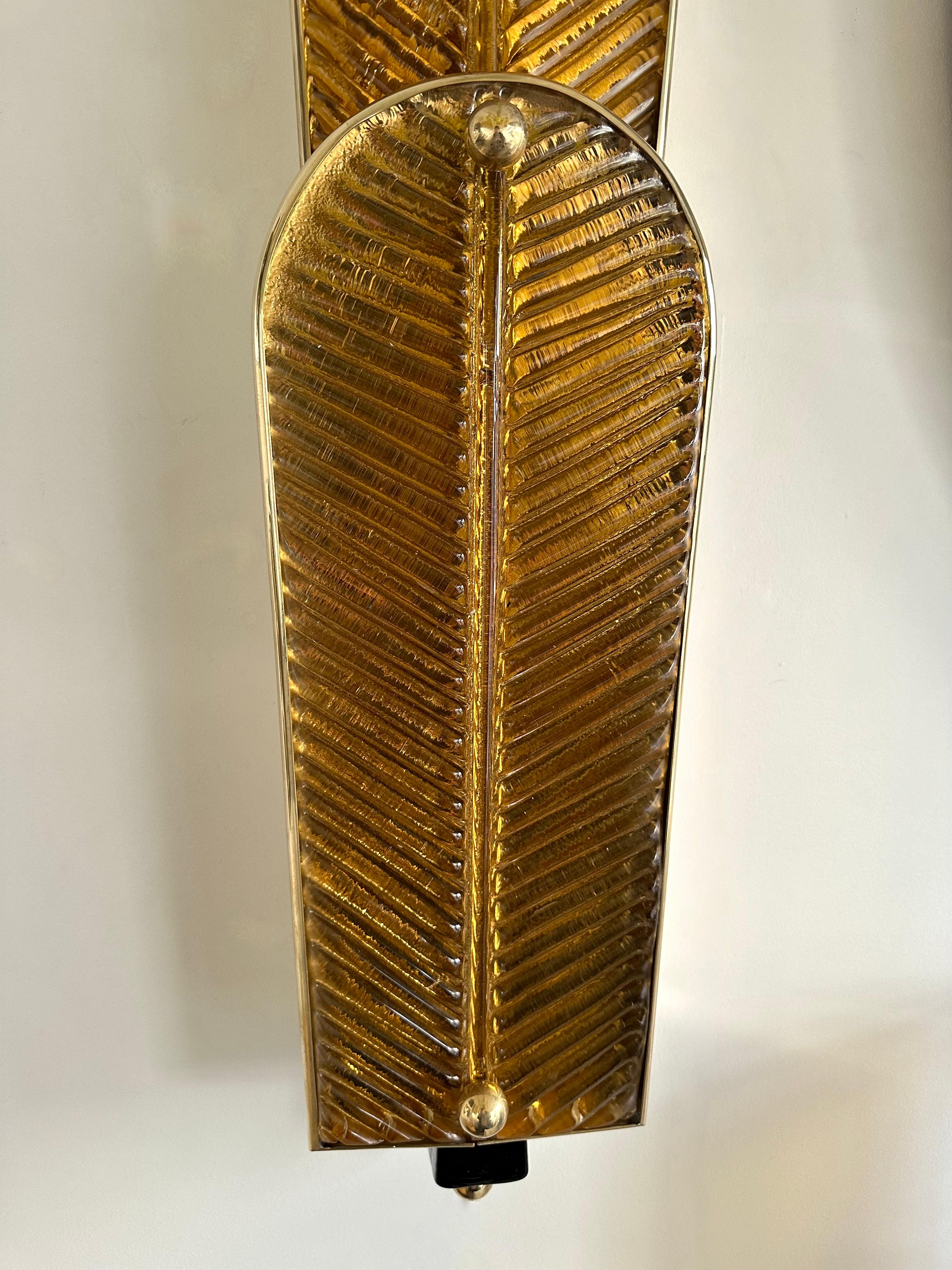 Grande coppia di applique contemporanee in vetro di Murano e ottone con foglie di palma; il vetro è circondato da ottone. Lavori contemporanei di un piccolo laboratorio artigianale di design italiano. Piccole imperfezioni dovute alla lavorazione