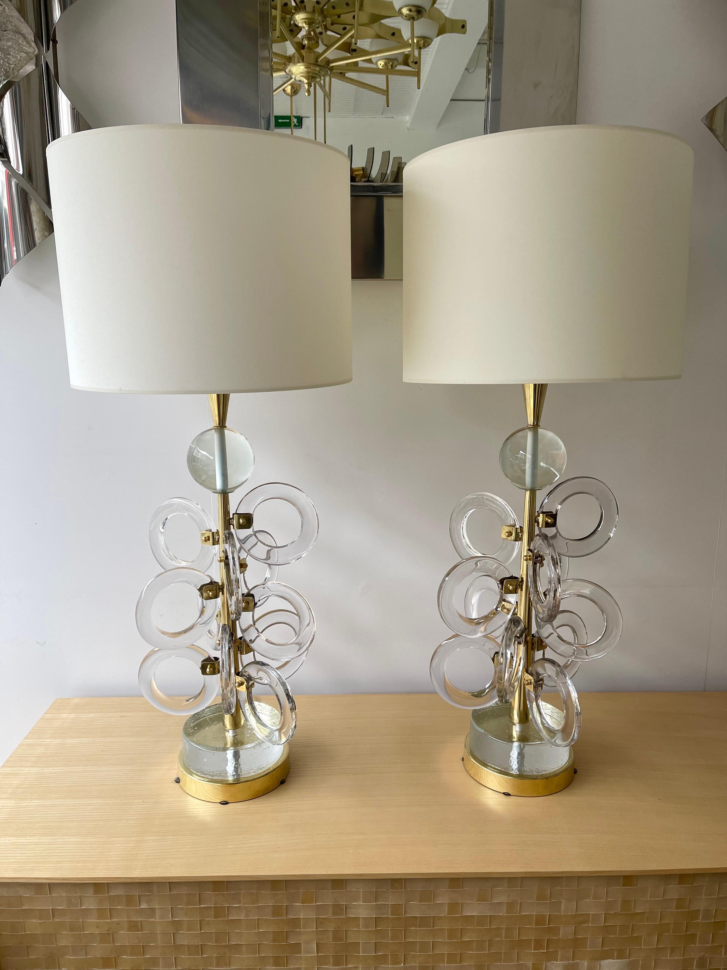 Pair of table or bedside brass lamps and Murano glass ring. Contemporary work from a small italian artisanal workshop.

Demo shades non included. Measurements in description with demo shades
Measurements lamp only H 69 x W 30 x D 30 cms.