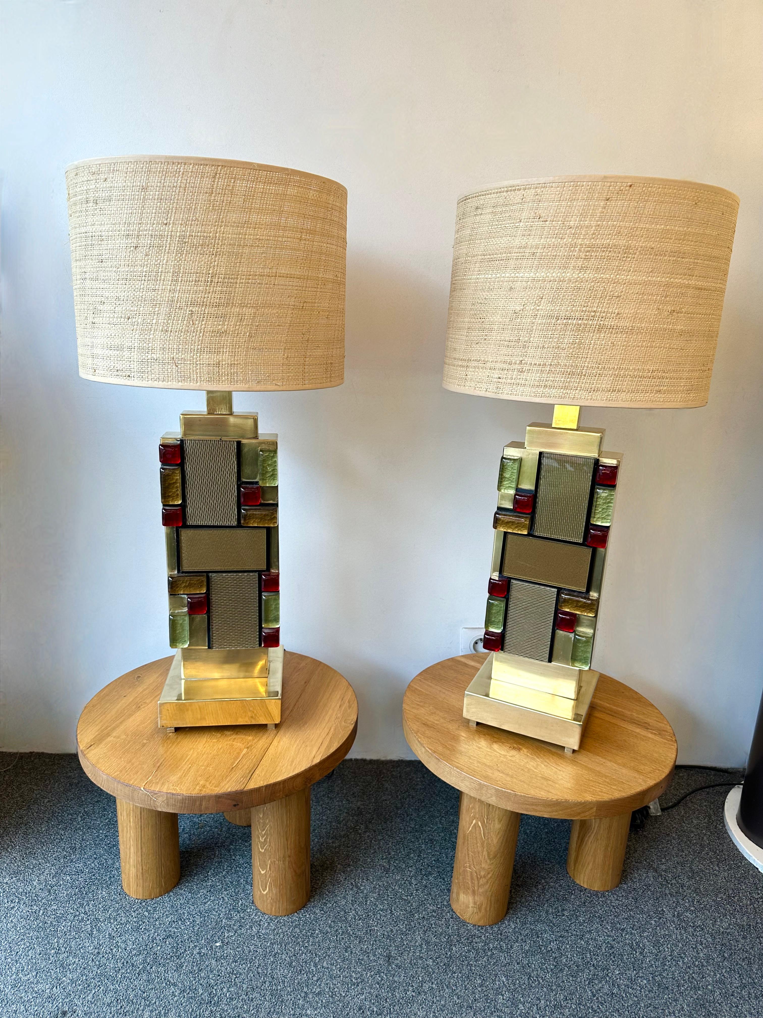 Pair of table or bedside brass lamps textured and Cabochon Murano Glass marquetry. Contemporary work from a small italian artisanal workshop, minor imperfections due to handmade, in a Mid-Century Modern Space Age Hollywood Regency mood.

Demo shades