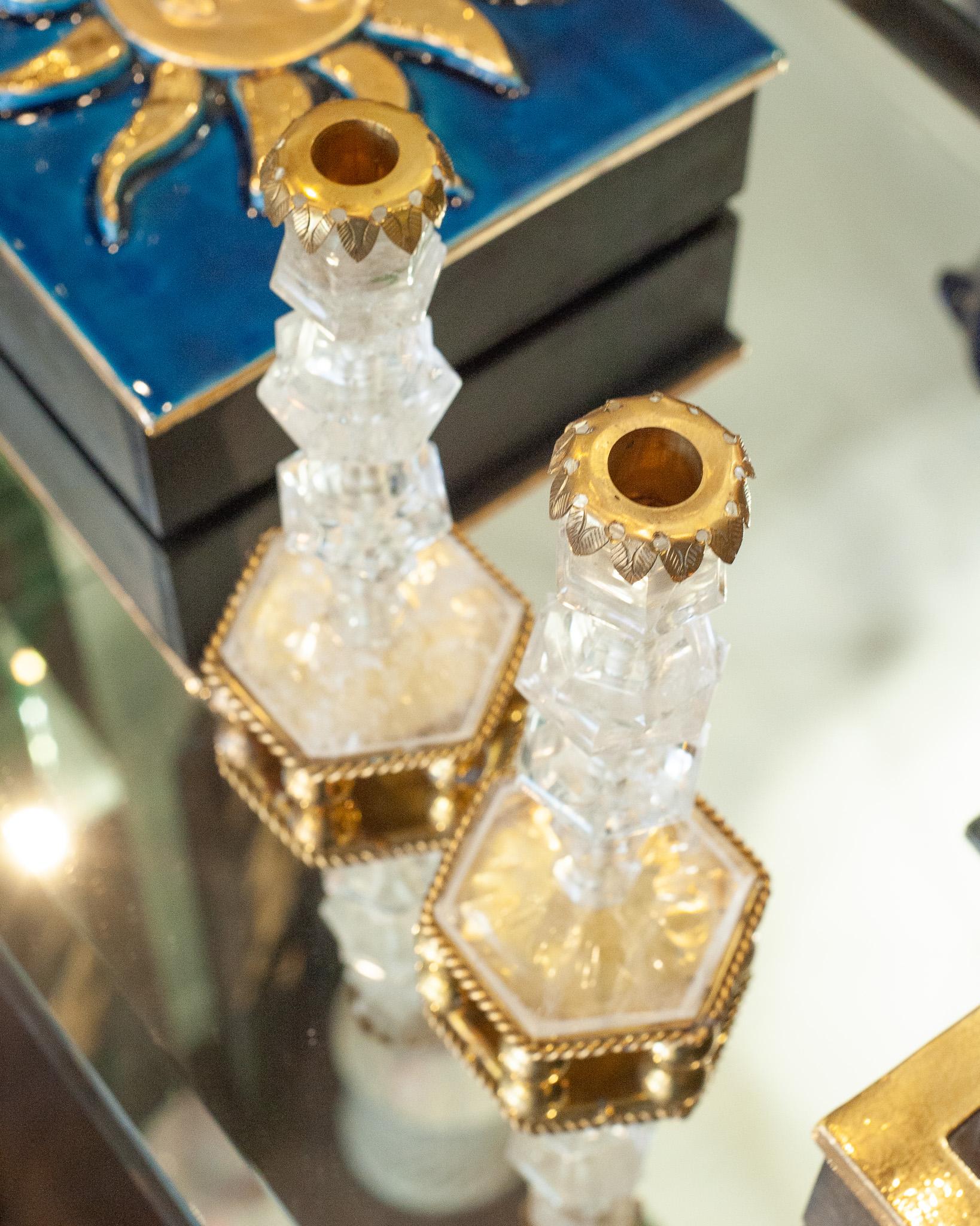 This pair of rock crystal and bronze candlesticks is a stunning blend of timeless elegance and refined craftsmanship. Sourced in Paris, each candlestick features finely carved rock crystal, known for its clarity and striking beauty. The rock crystal