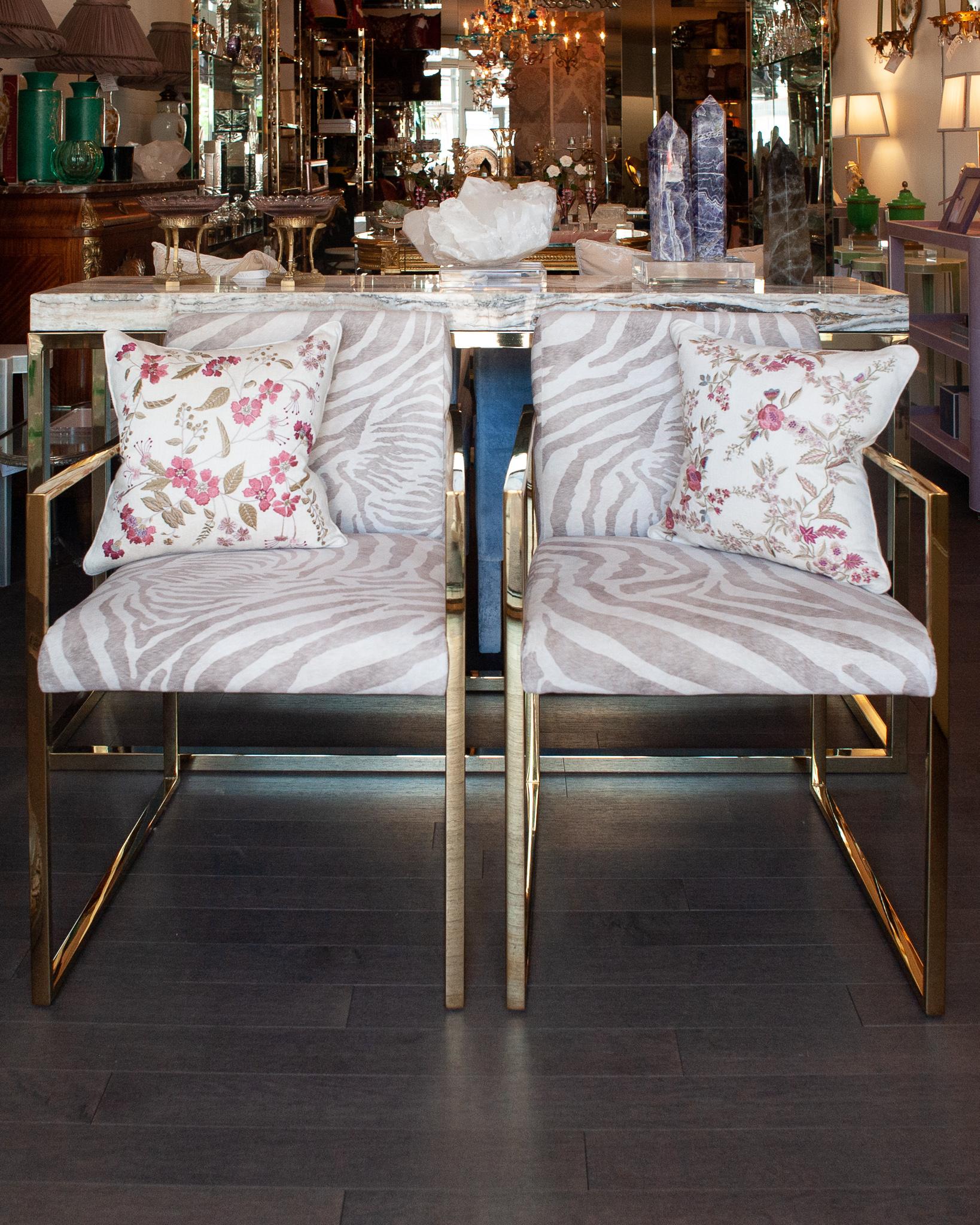 A gorgeous pair of contemporary polished brass armchairs with zebra print upholstered seats. With clean sleek lines and a Mid Century Modern inspiration, these armchairs are a timeless combination of material and finish. The zebra print upholstery