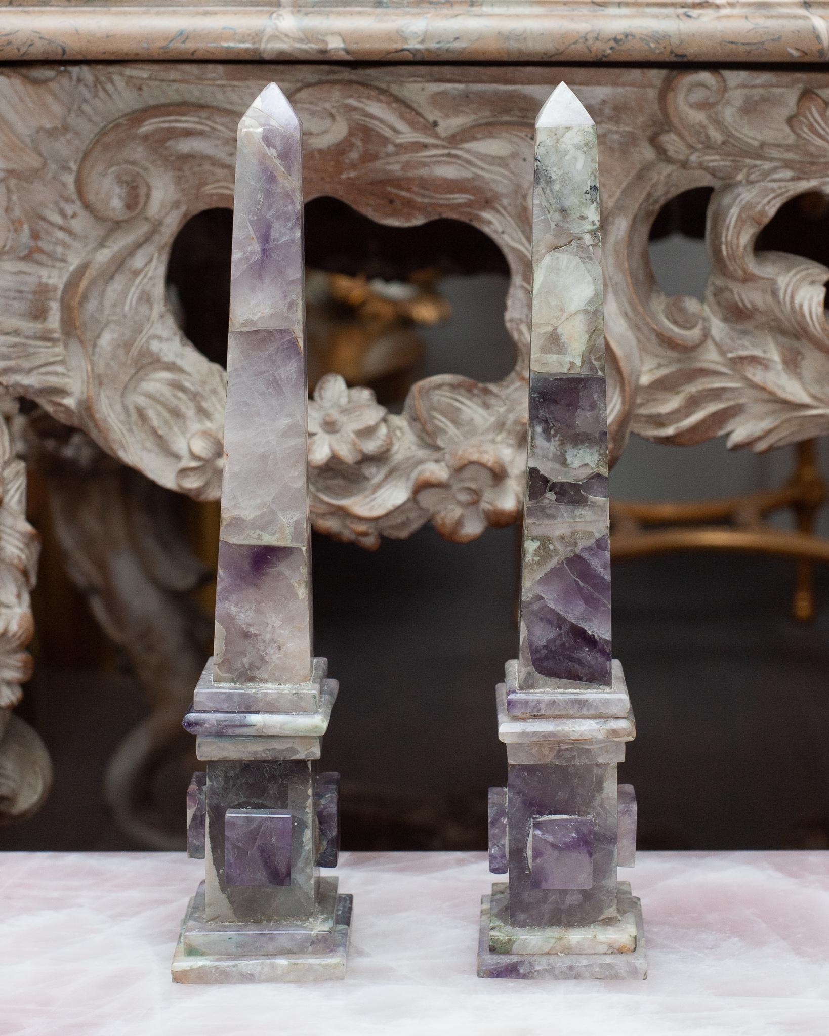 Cette paire d'obélisques spectaculaires est fabriquée en améthyste,  cristal semi-précieux translucide de couleur lavande à mauve qui est une forme de quartz que l'on trouve dans de nombreux endroits du monde et qui se forme sous forme de cristaux