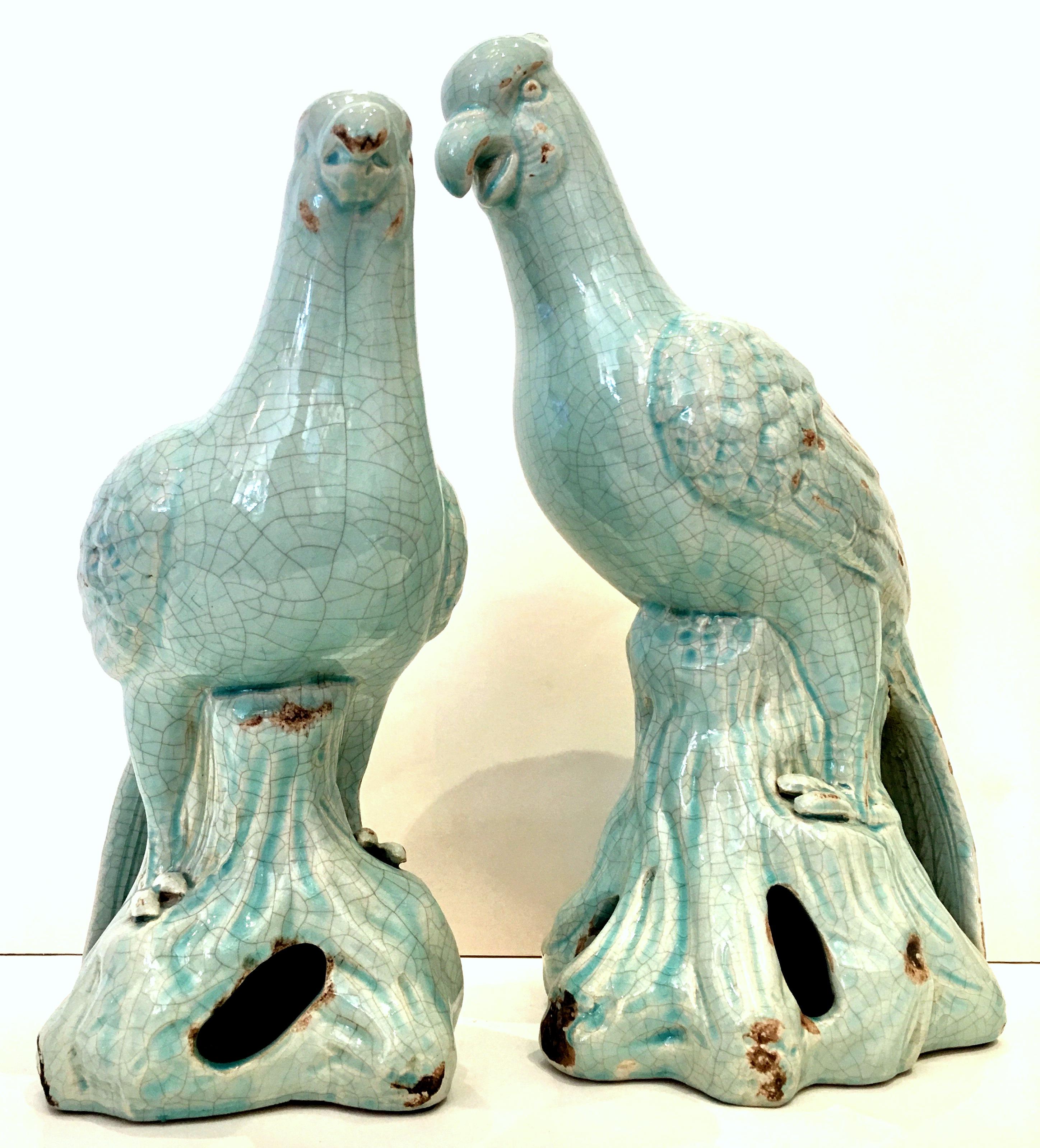 21st Century Contemporary Pair Of Robins Egg Blue Ceramic Glaze Bird Sculptures. This pair of perched bird sculptures feature a faux aged patina of rust and crazing.  The smaller of the pair measures, 13