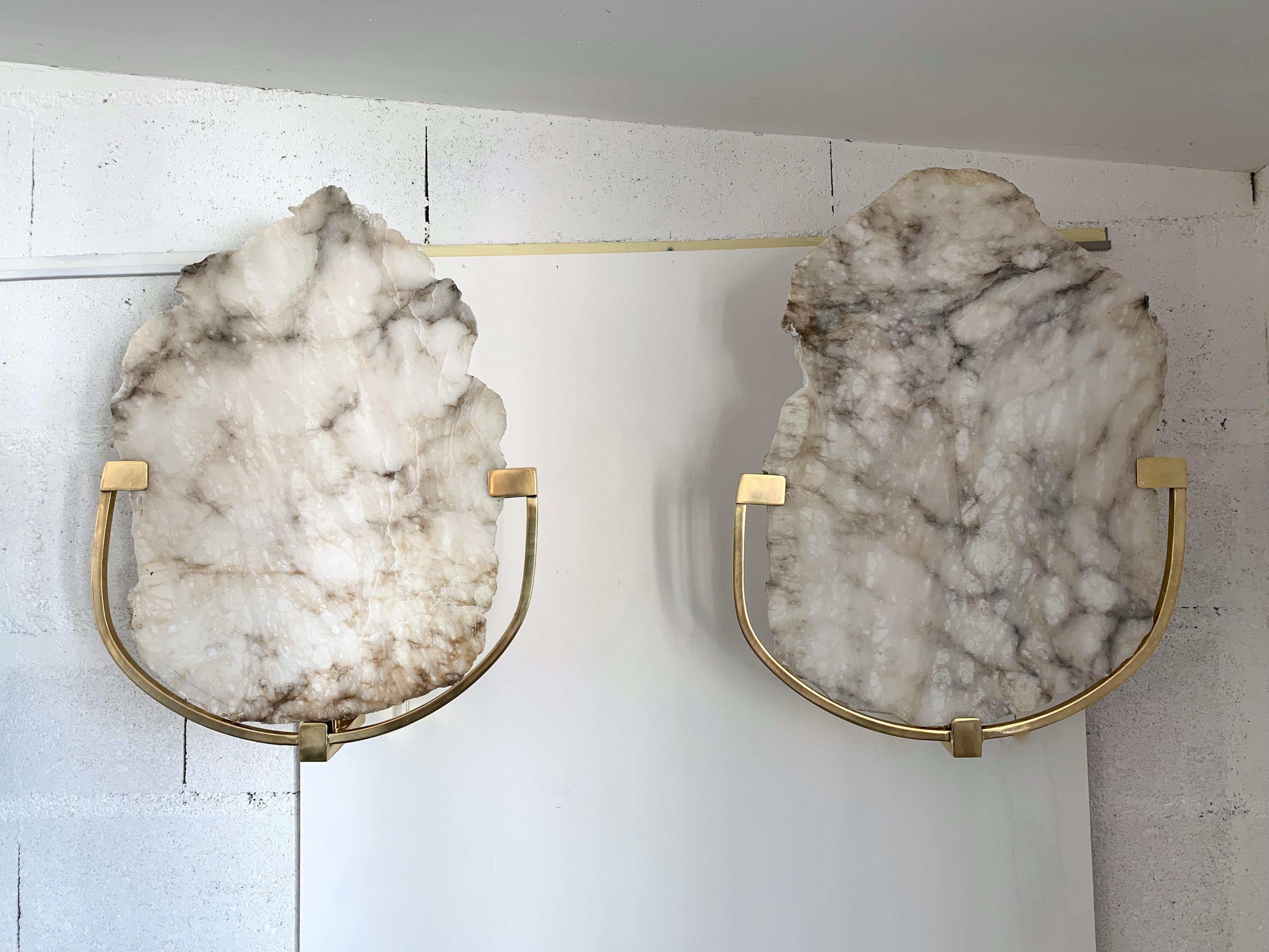 Pair of alabaster wall lights sconces, brass structure, each piece are different as natural cut of alabaster but enough coherent to make a pair. Few exclusive Italian artisnal production.