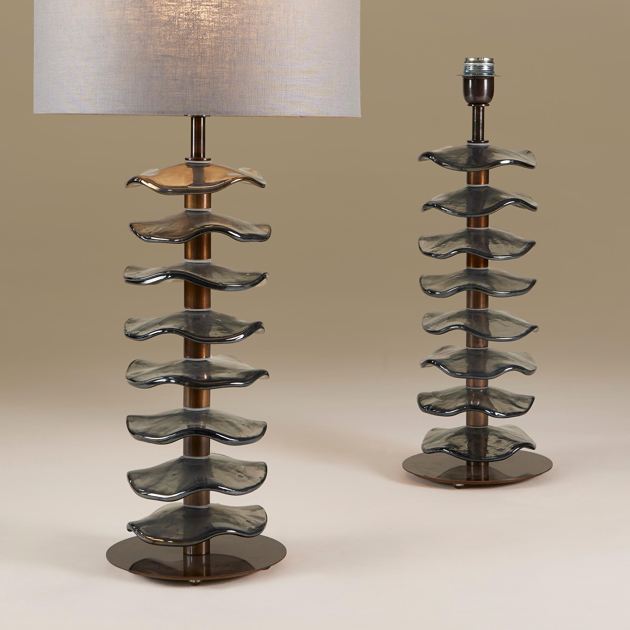Imposantes Paar schicker Tischlampen, bestehend aus acht einzelnen, handgefertigten, hellgrauen Murano-Blütenscheiben mit dezent schillerndem Glanz. Jede sitzt auf einem Stiel aus dunklem Messing mit einem einfachen runden Messingfuß.

Lampenschirme