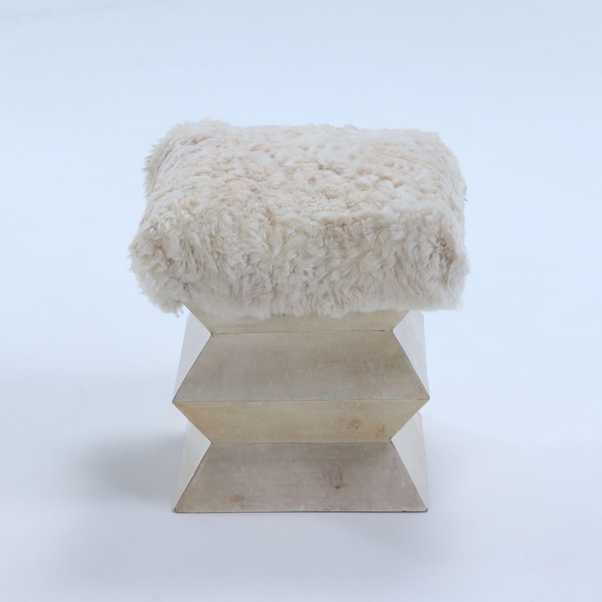 A Contemporary parchment covered stool of architectural form having goat hair upholstery.