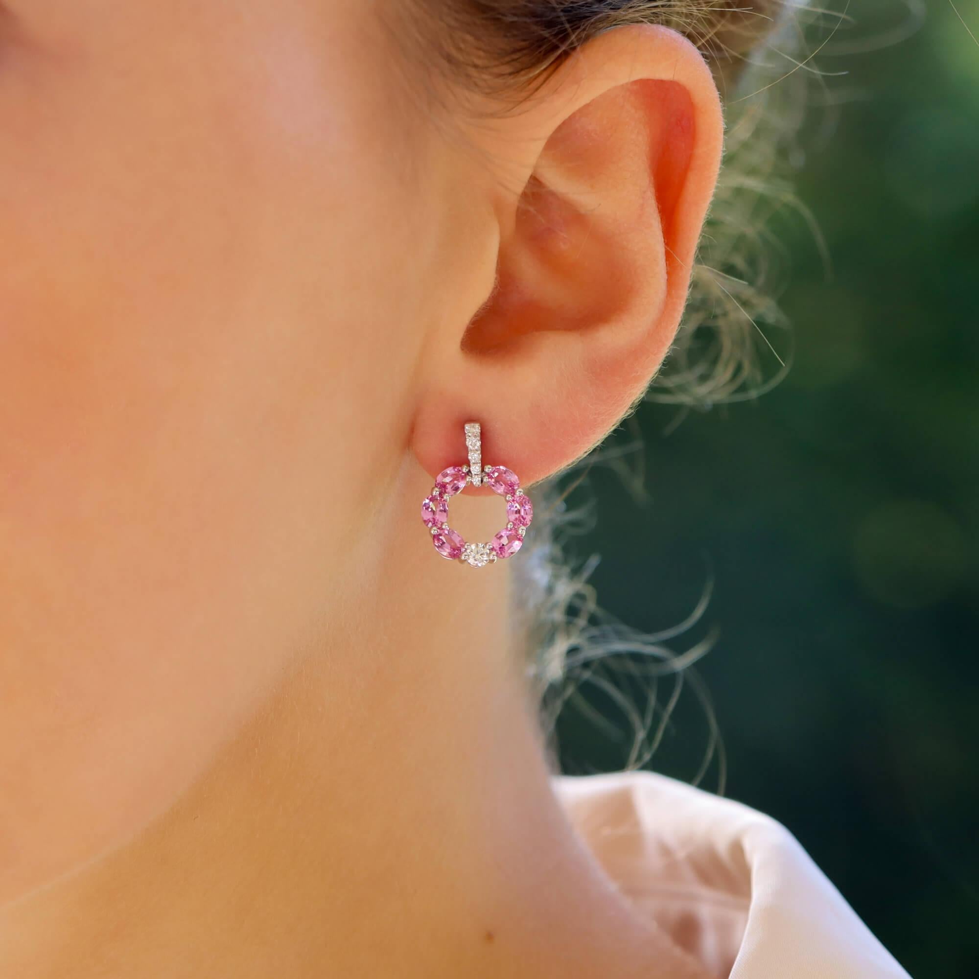 A beautiful pair of pastel pink sapphire and diamond circular drop earrings set in 18k white gold.

The earrings are predominantly set with a white gold hoop, set throughout with oval cut pastel pink sapphires; all of which are perfectly matched in
