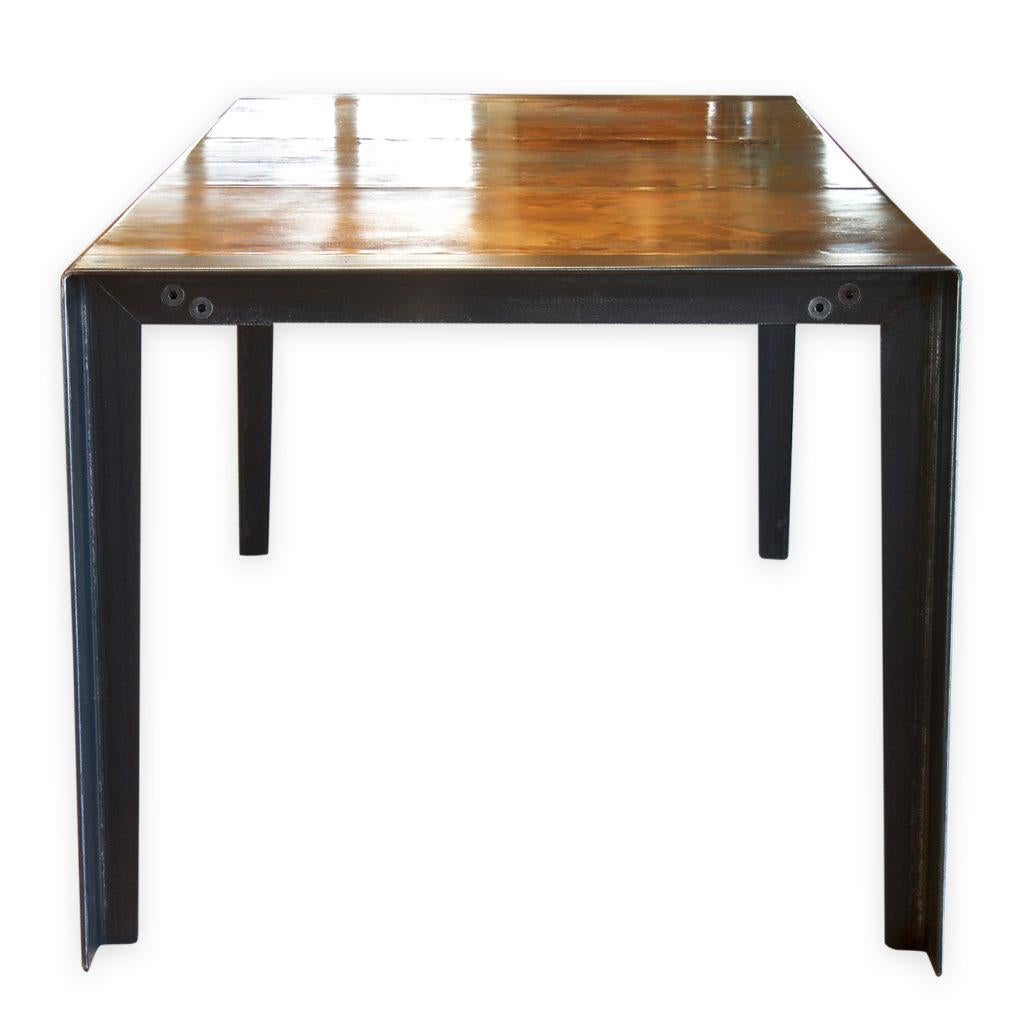 An Andrew Nebbett Designs standard sized contemporary copper-top dining table with angled profile edges, featuring simple steel angle legs. This table is made using Watermark Copper patination to the table surface. This dining table (or kitchen