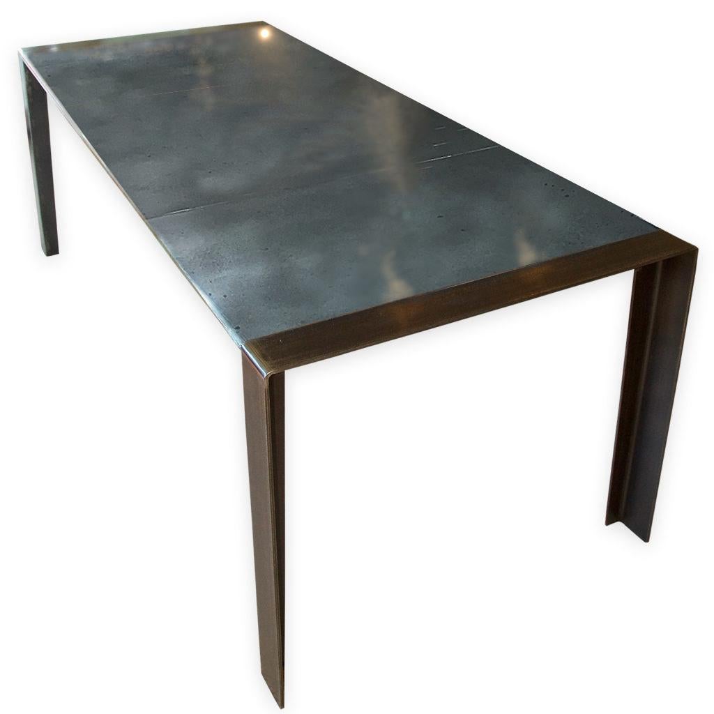 An Andrew Nebbett Designs standard sized contemporary zinc-top dining table with angled profile edges, featuring simple steel angle legs. This table is made using patinated zinc for the table surface. This dining table (or kitchen table) is