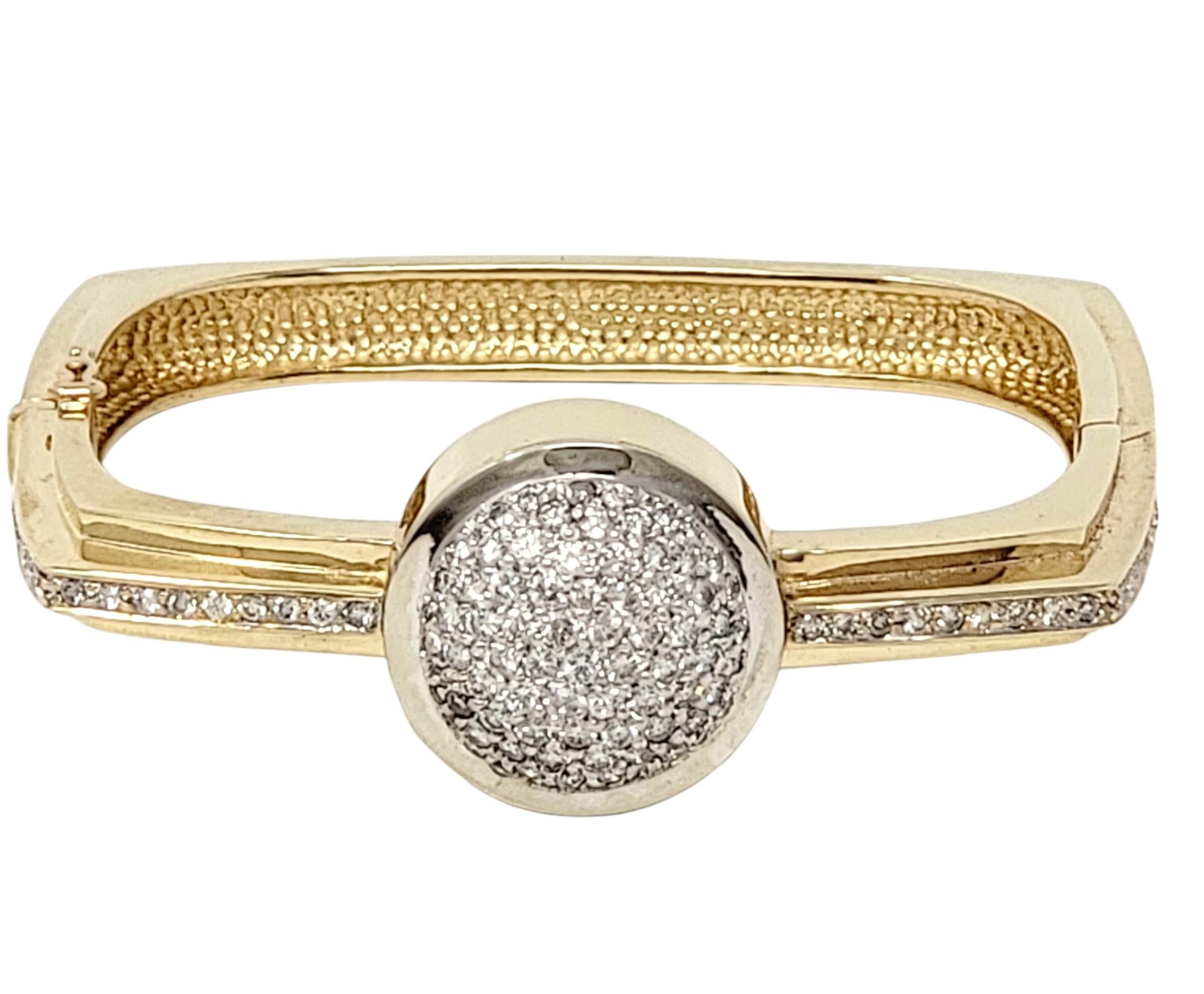 Ultra contemporary pave diamond bangle bracelet in two tone 14 karat gold. The sleek, modern design features a squared yellow gold design accented by a single row of glittering icy white pave diamonds. The bold focal point at the center features a