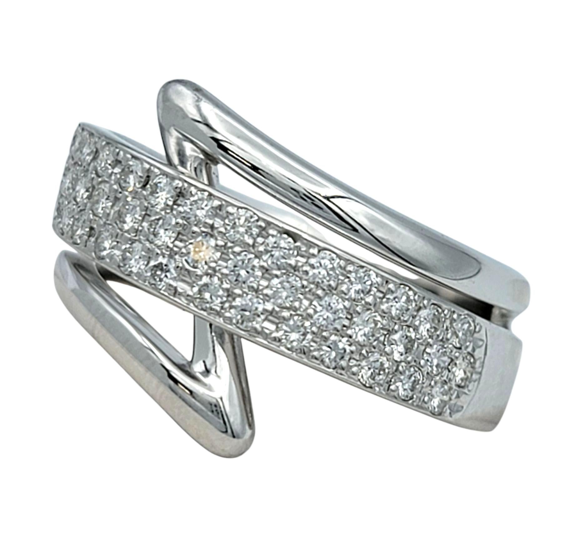 Ring Size: 7

This platinum ring features an eye-catching crossover design with two sculptural bands that gracefully bypass at an angle. The center band is encrusted with multiple rows of round brilliant-cut diamonds, set closely together in a pavé