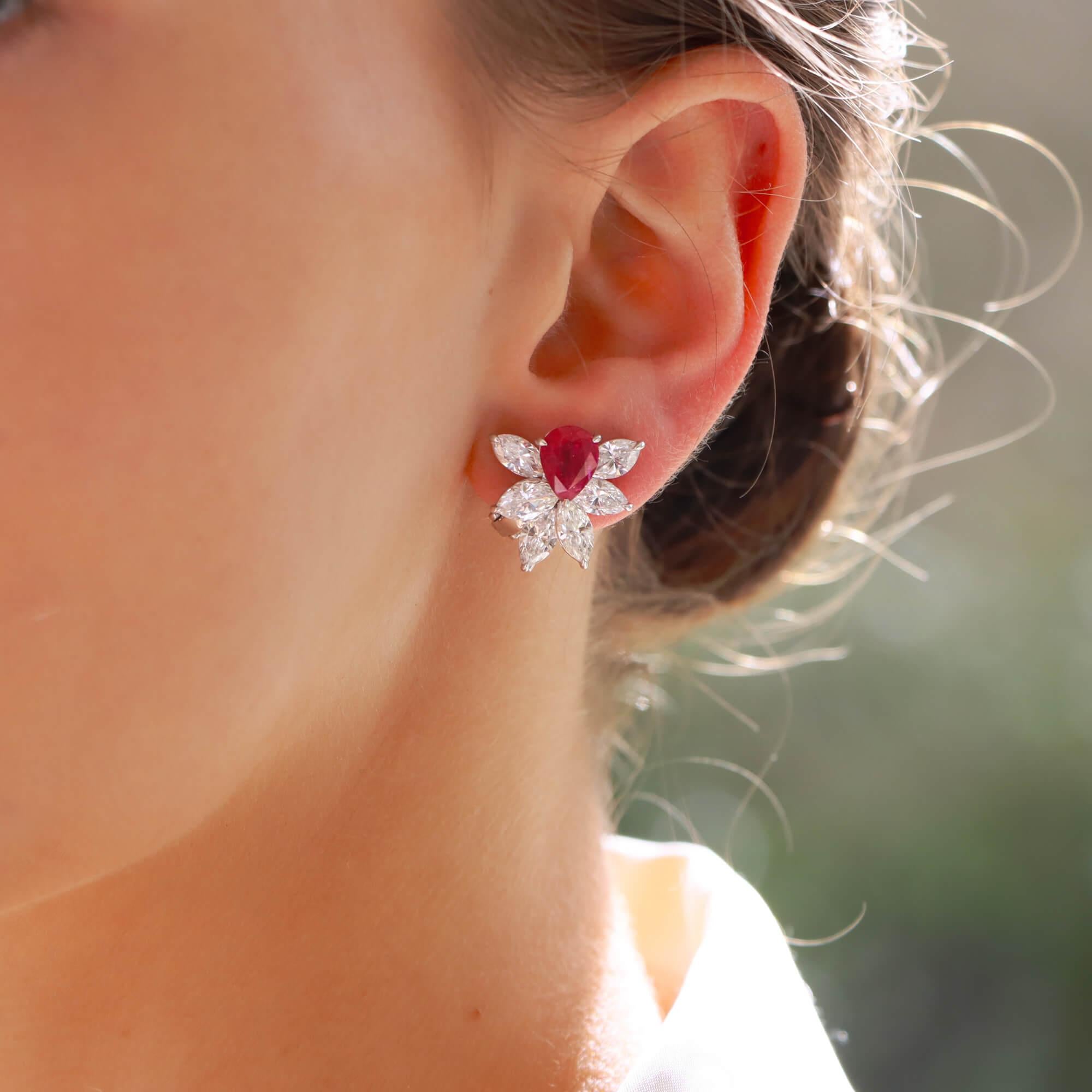 A stunning pair of pear shaped ruby and marquise cut diamond cluster earrings in platinum.

Each earring features a single pear shaped ruby of bright pink red colour with 6 marquise shaped diamonds in a half cluster spray to the bottom of each