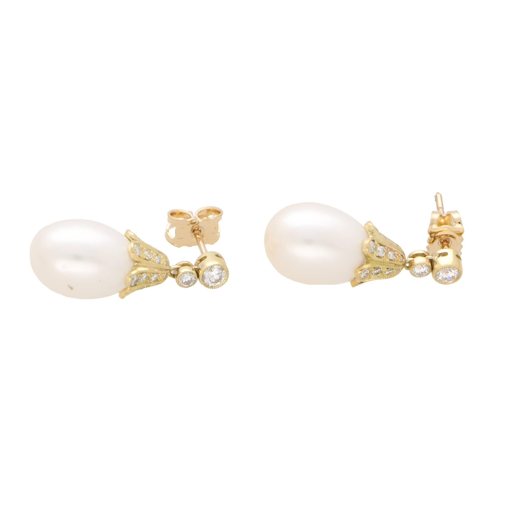 A beautiful pair of white cultured pearl and diamond drop earrings set in 18k yellow gold.

Each earring is firstly composed of a rub over round brilliant cut diamond stud, secured to reverse with a post and butterfly fitting. Hanging freely from